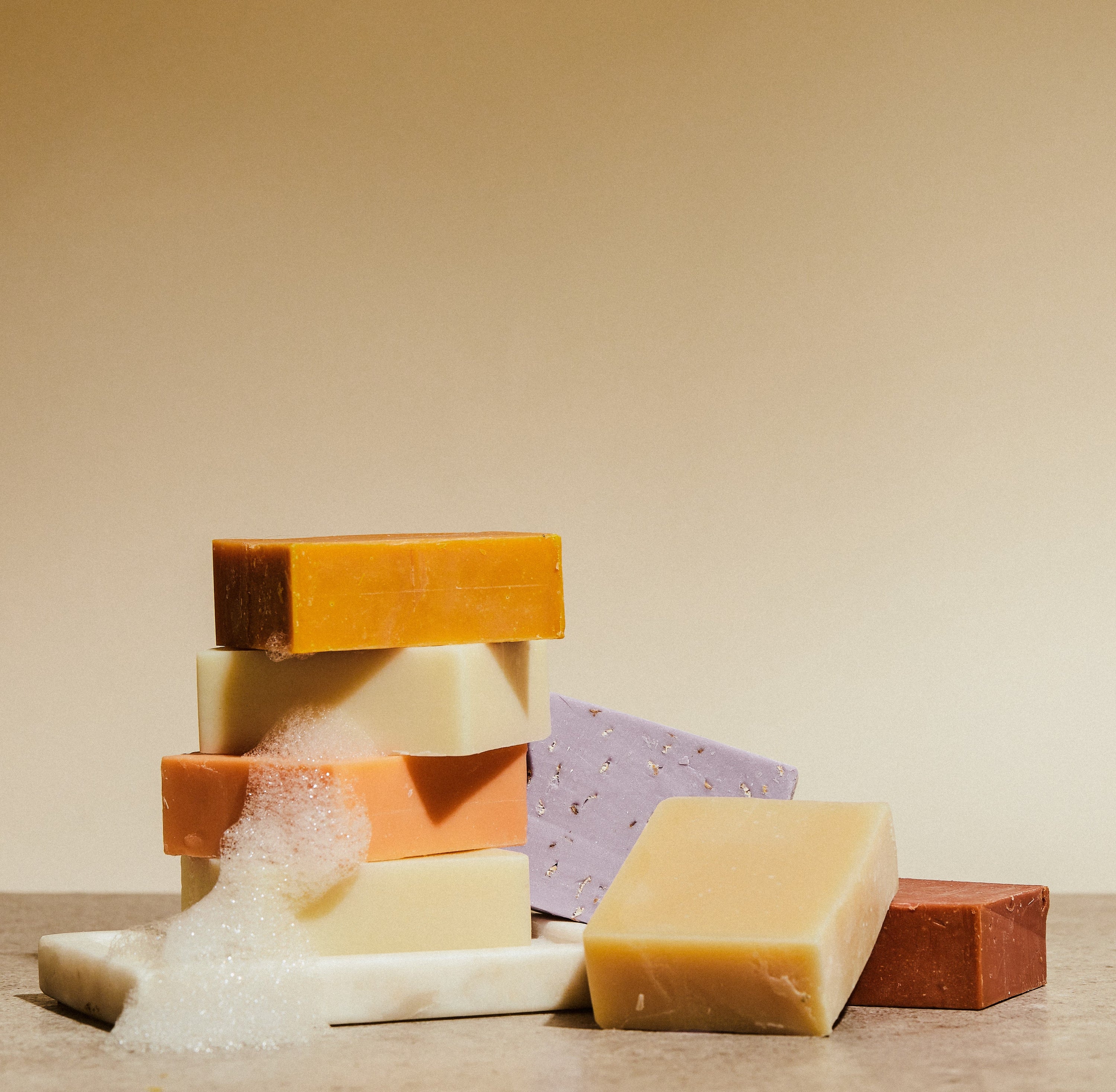 Stack of rectangular bar soaps in orange, white, purple, tan, and brown tones.