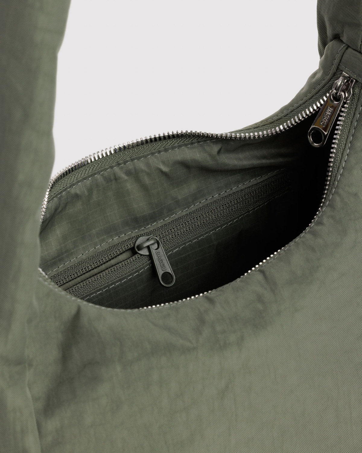 Olive green nylon bag interior with silver zipper and hanging logo tag