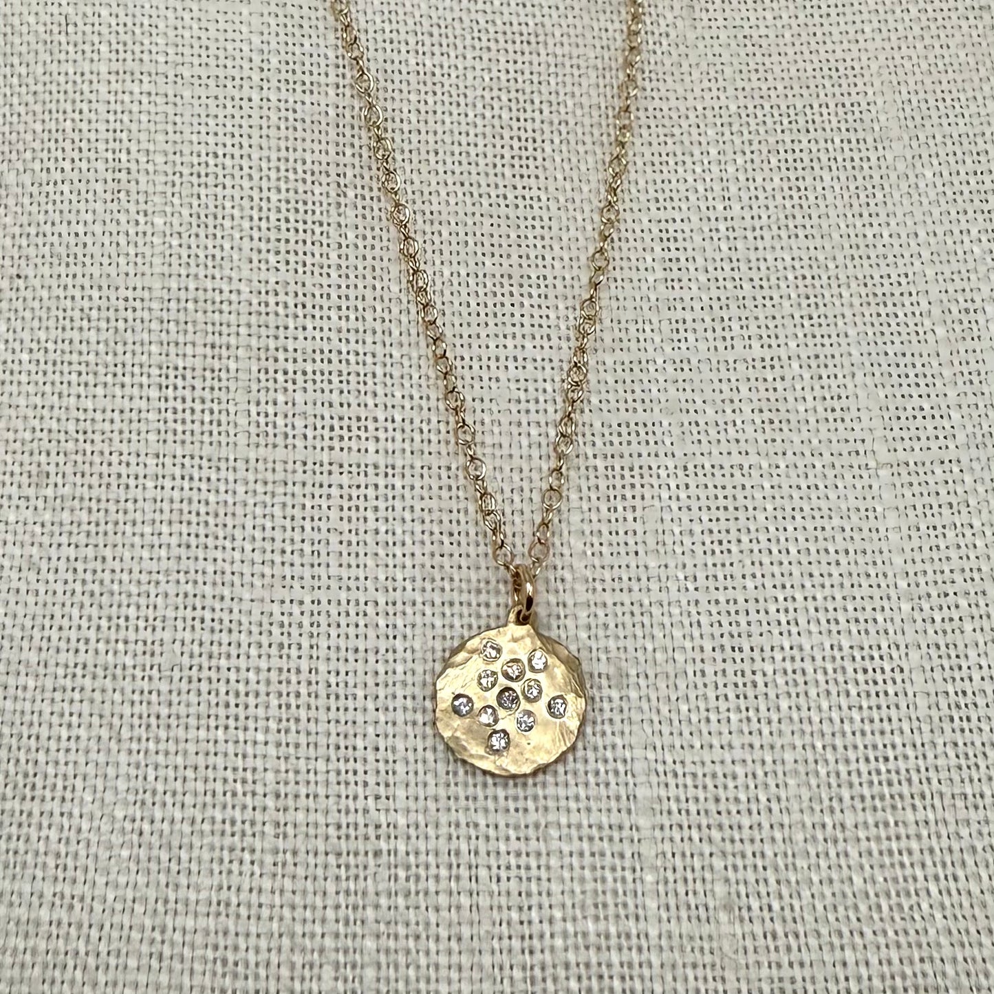 Gold disc pendant necklace with small diamond-studded pattern and fine chain