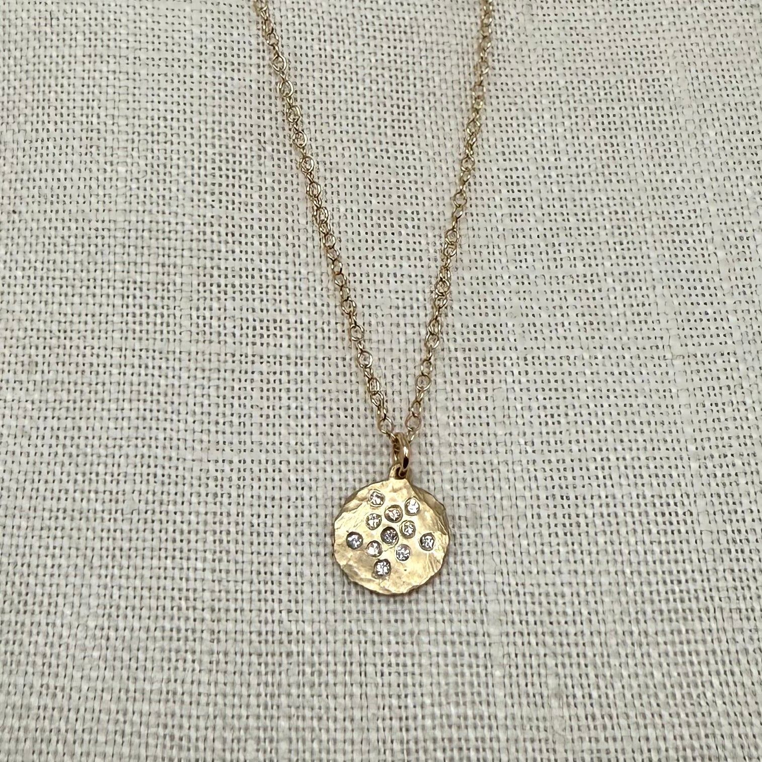 Gold disc pendant necklace with small diamond-studded pattern and fine chain