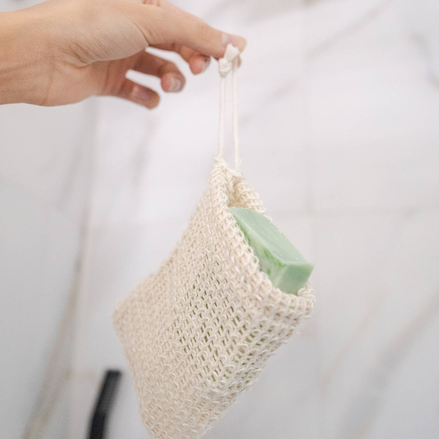 Casa Agave woven soap exfoliating bag held in hand, cream mesh pouch with soap inside