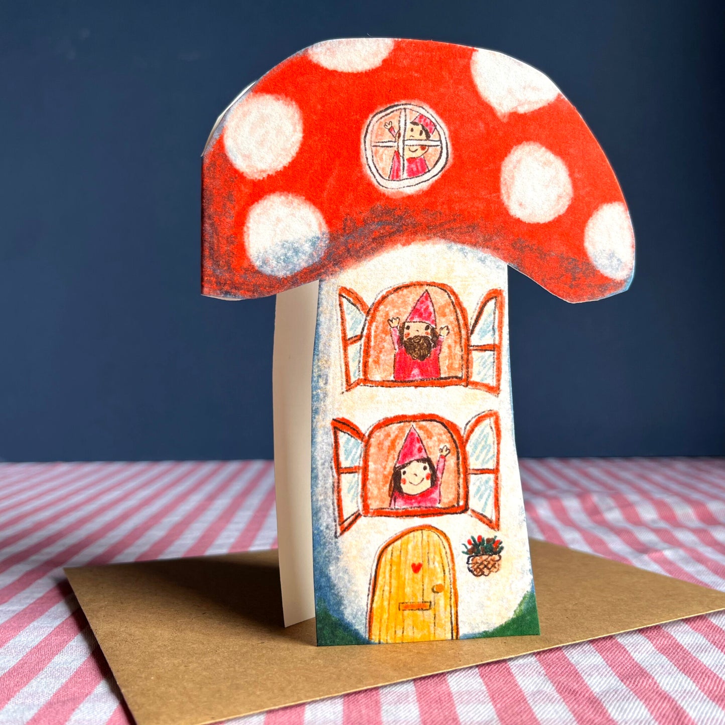 Toadstool-themed greeting card with red white-spotted mushroom top and house door illustration