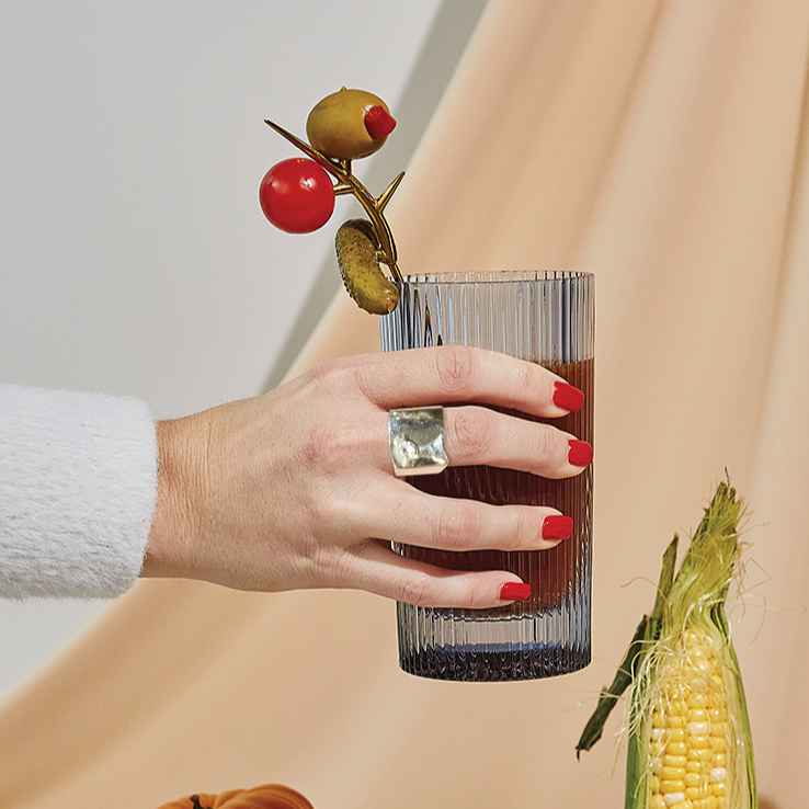 Blue ribbed highball glass held in hand, with vertical fluted sides and thick base