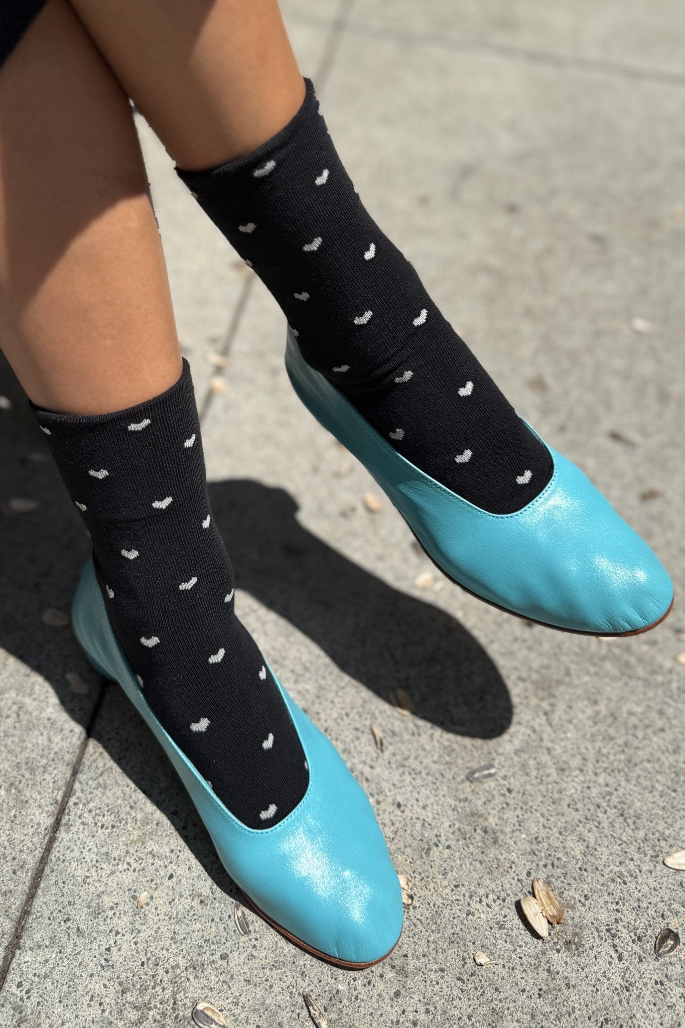 Black sneaker socks with cream hearts, worn with blue shoes