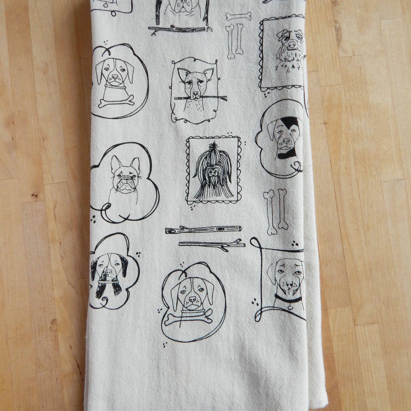 Dog kitchen tea towel section with line-drawn dog faces, bowls, and kitchen utensils.