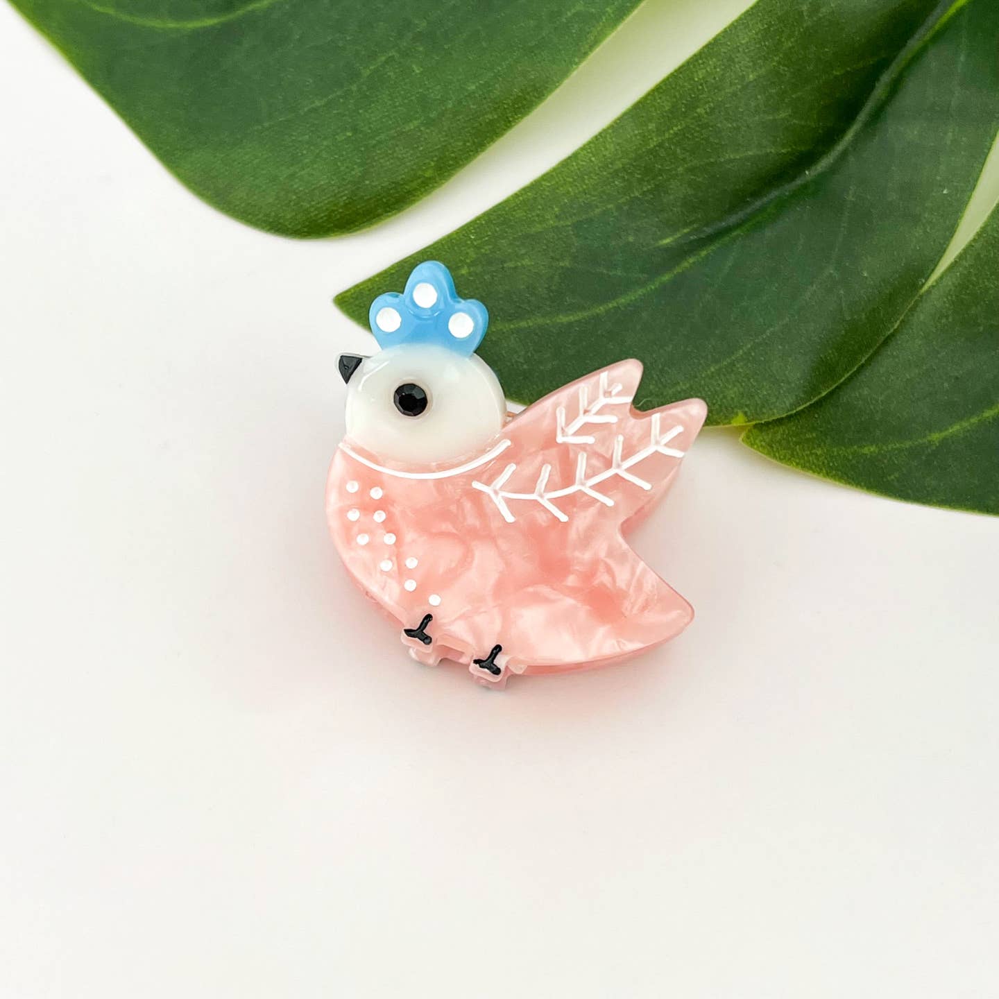 Pink mini bird hair claw clip with blue crown, white eyes, and snowflake wings