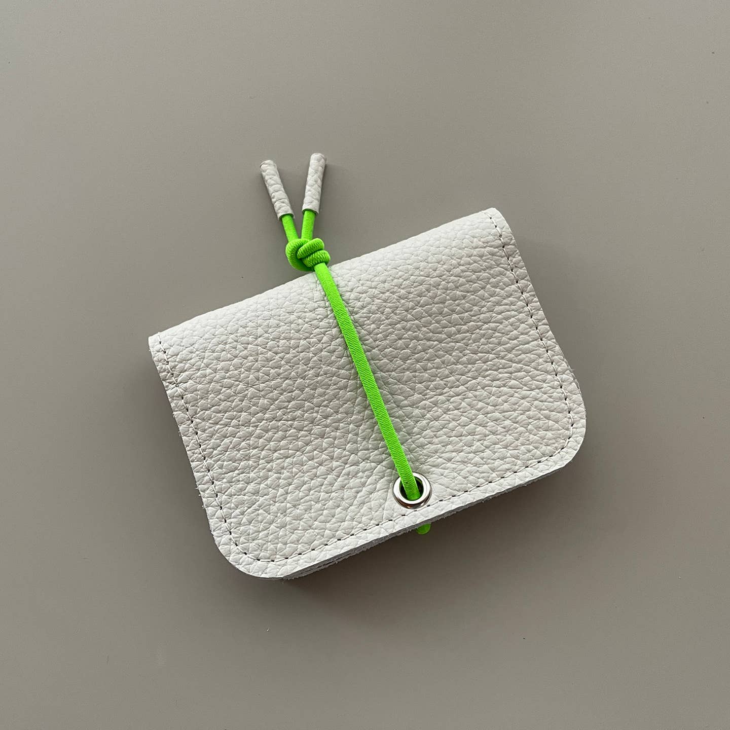 White leather mini wallet with knot closure and textured fold-over front
