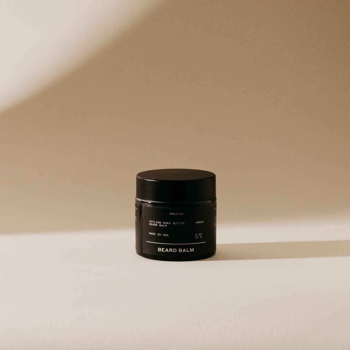 Beard balm jar, black container with dark lid and centered label