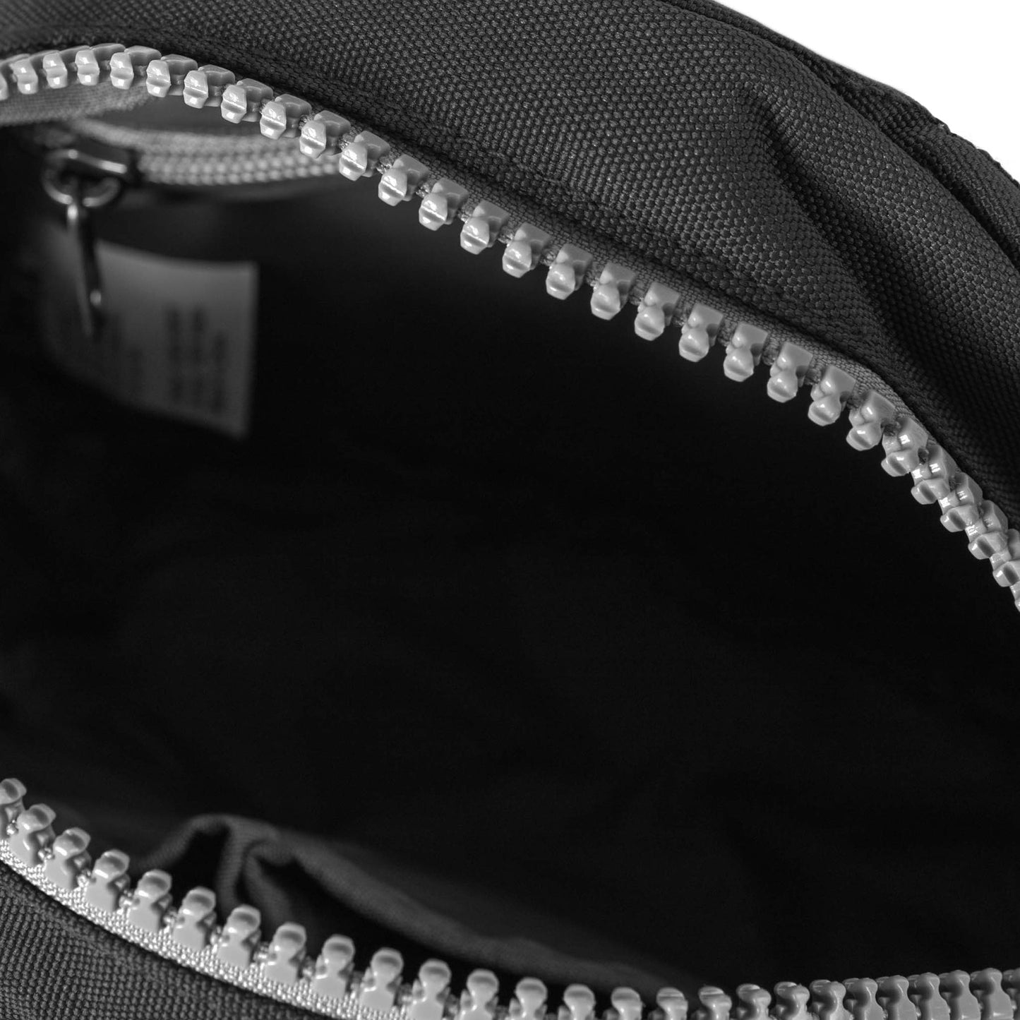 Recycled canvas crossbody bag close-up, black interior with silver zipper teeth