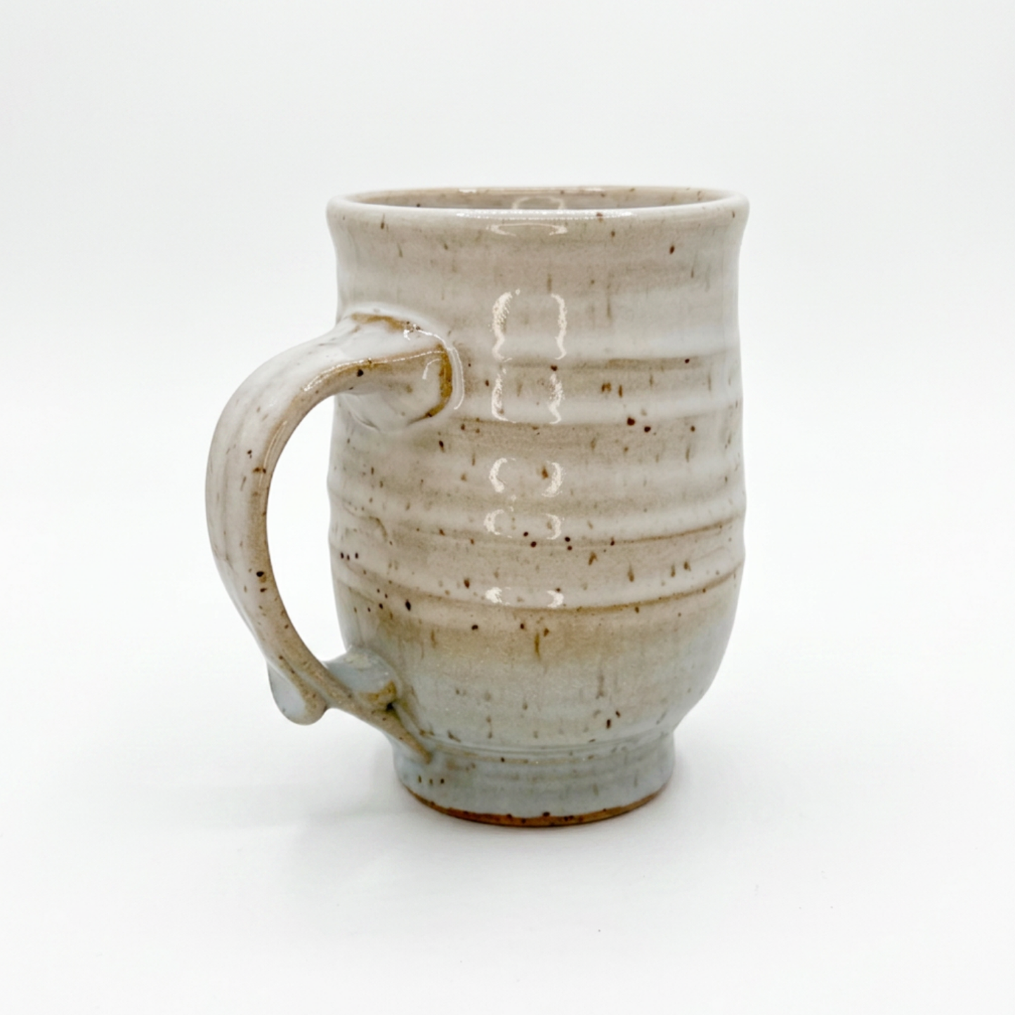 Speckled ceramic mug with left handle, off-white glaze with drips and dark specks