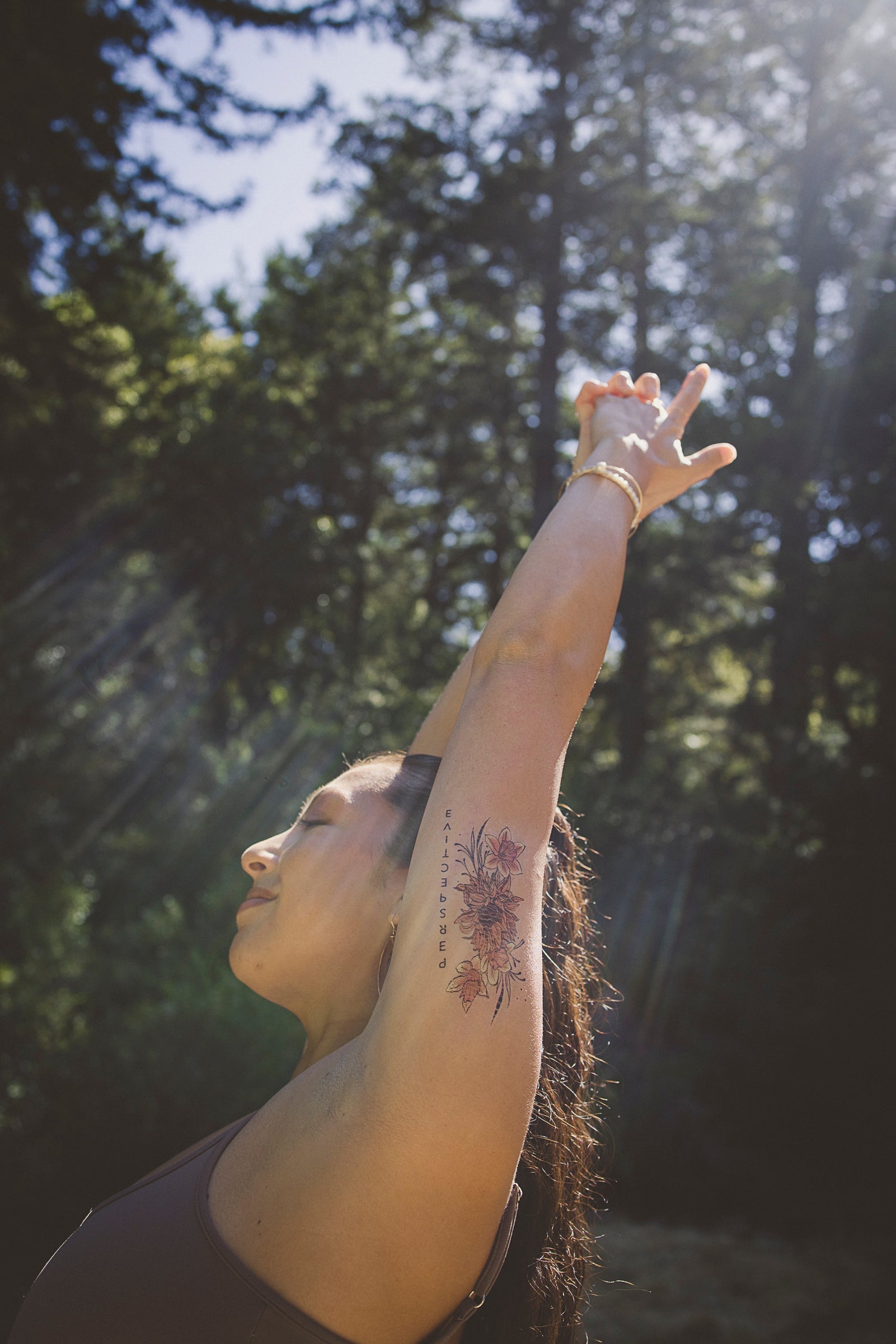 Small floral temporary tattoo across forearm with fine line petals and leaves