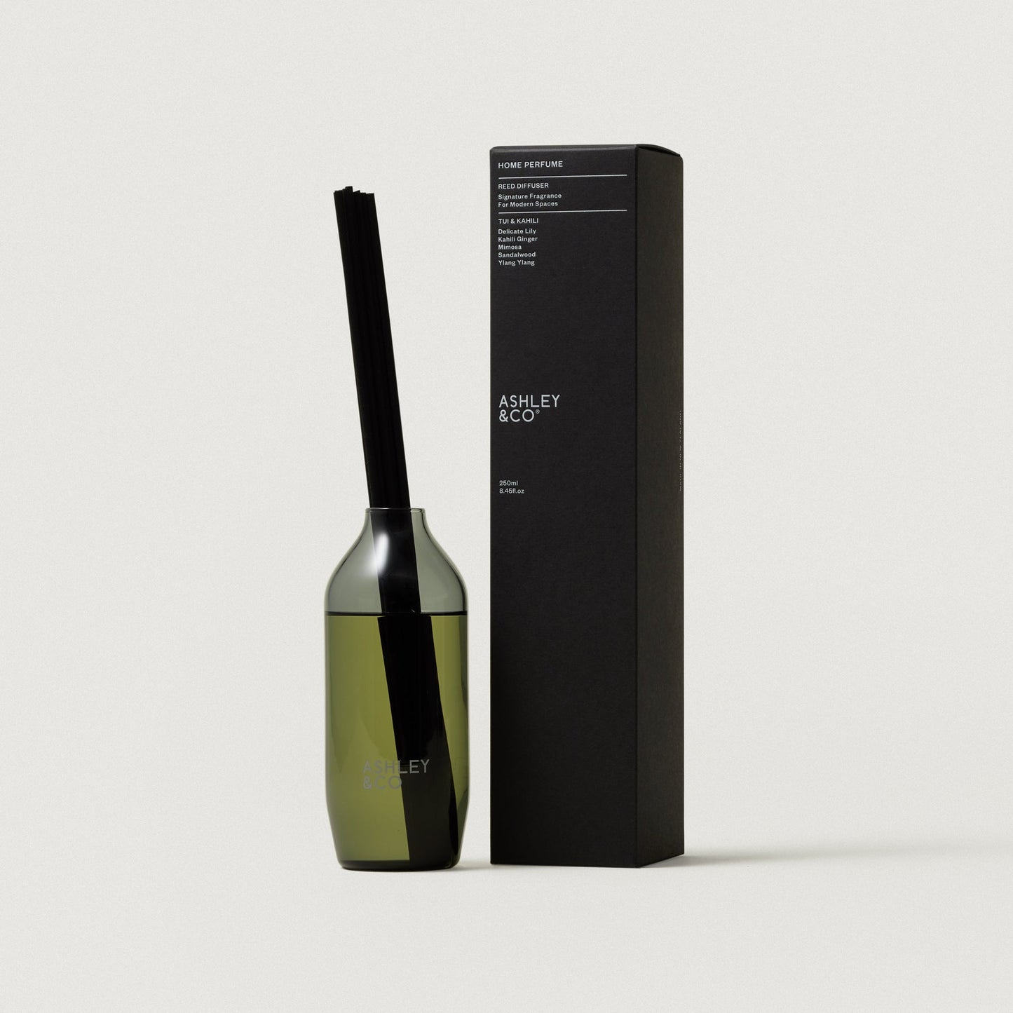Glass reed diffuser bottle with black reeds beside rectangular Ashley & Co box