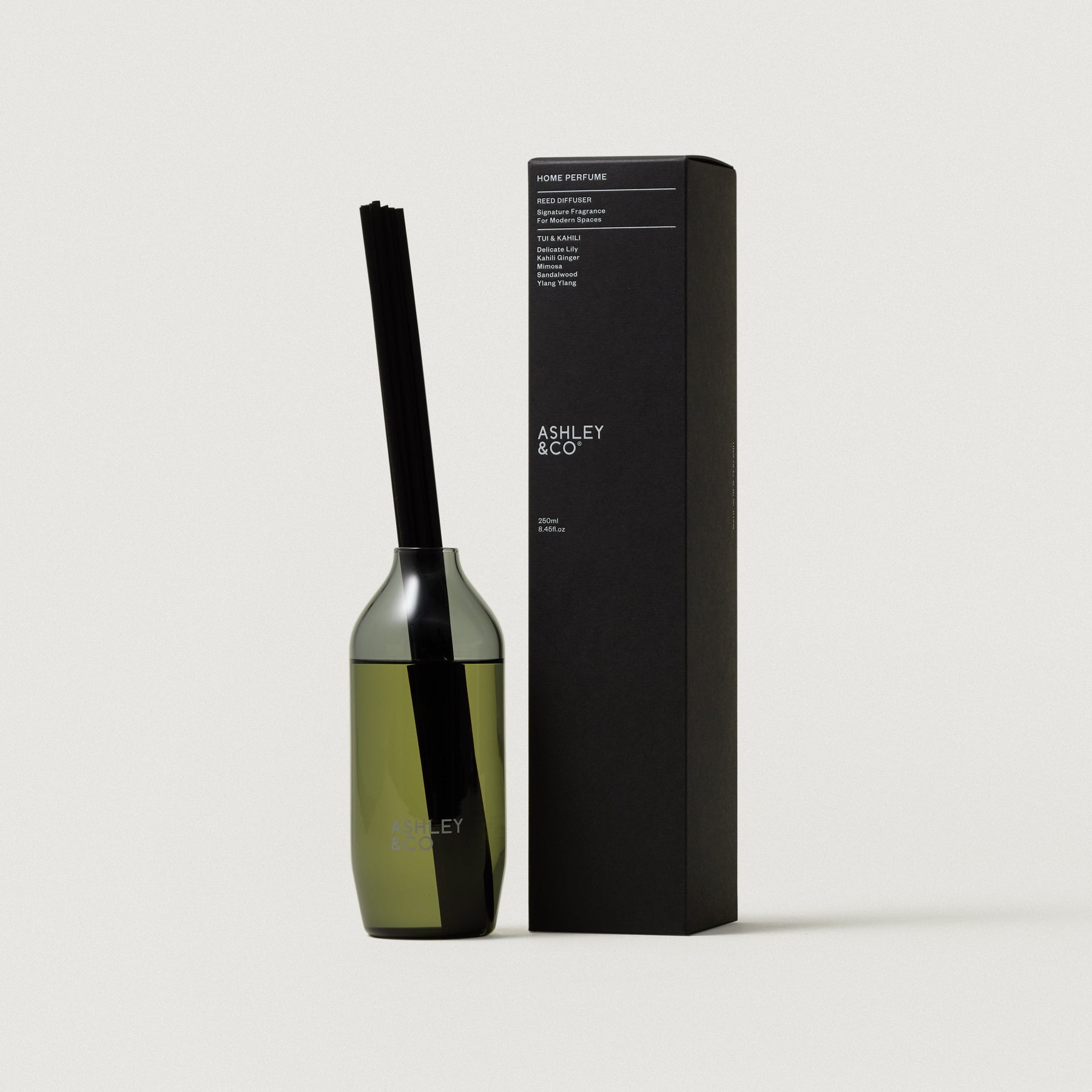 Glass reed diffuser bottle with black reeds beside rectangular Ashley & Co box