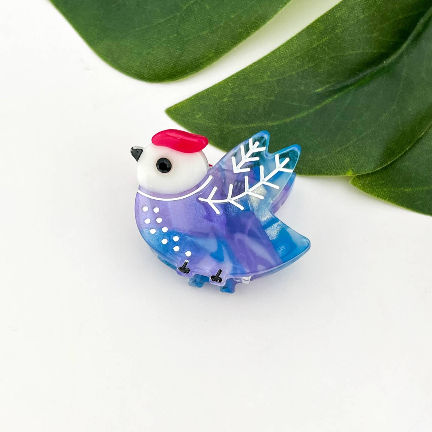 Purple and blue bird hair claw clip with red crown and white snowflake wing detail