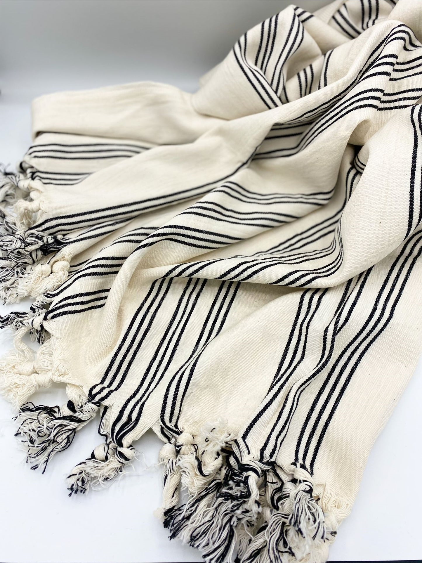Folded cream throw blanket with black stripes and chunky tassel fringe