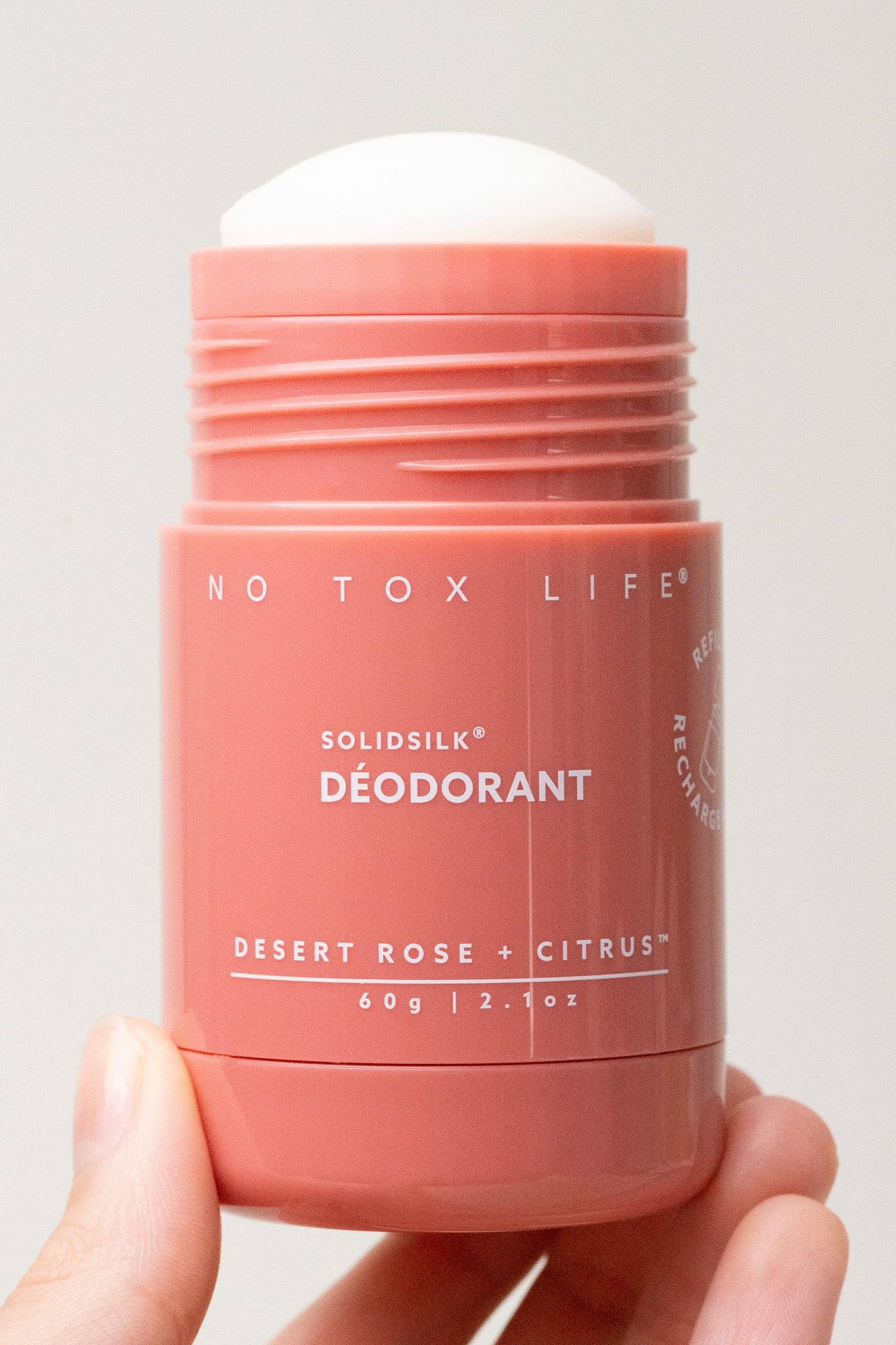 Refillable solid deodorant stick in coral pink with Desert Rose + Citrus label