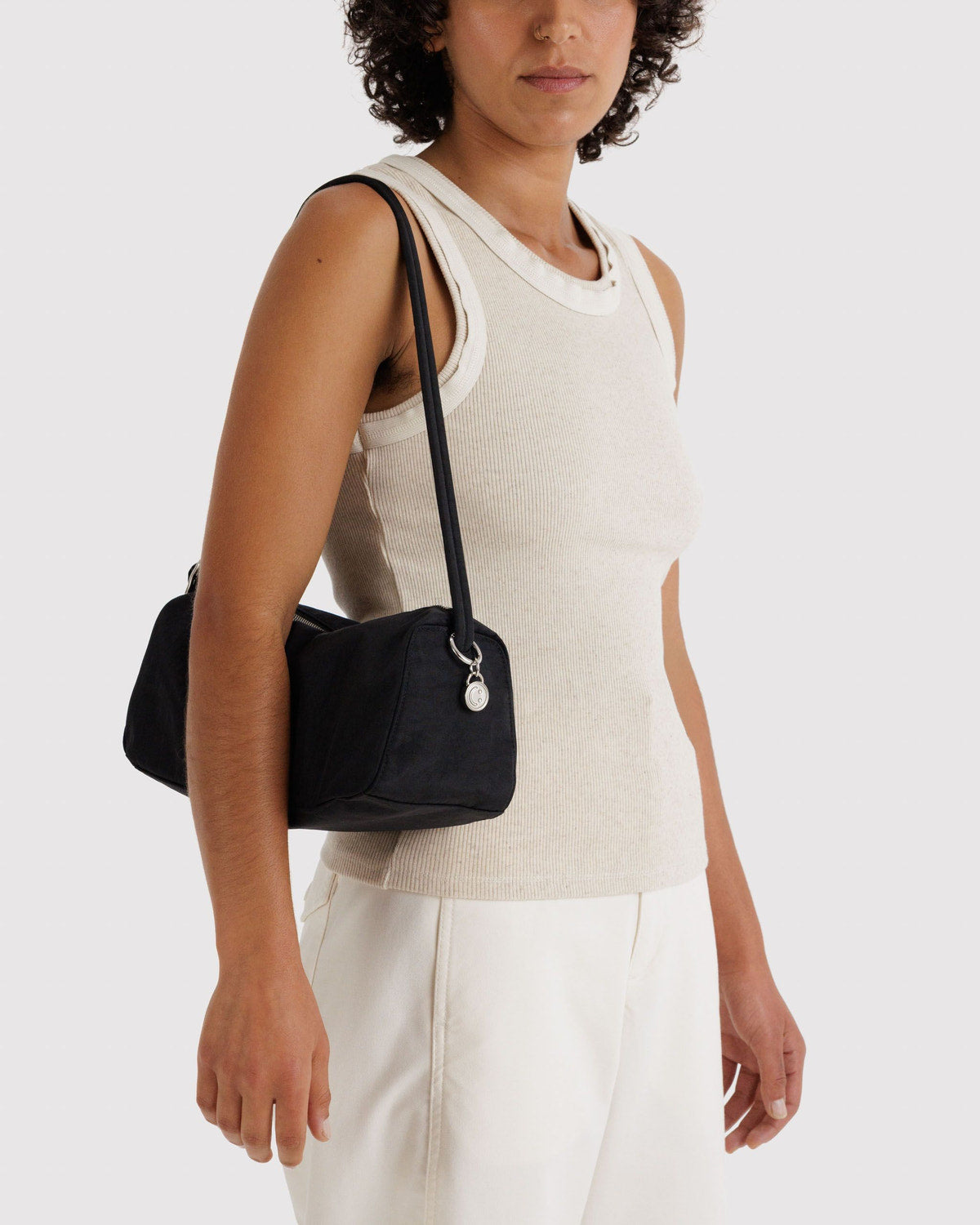 Black nylon loaf bag worn over shoulder; curved handle, side strap, top zipper.