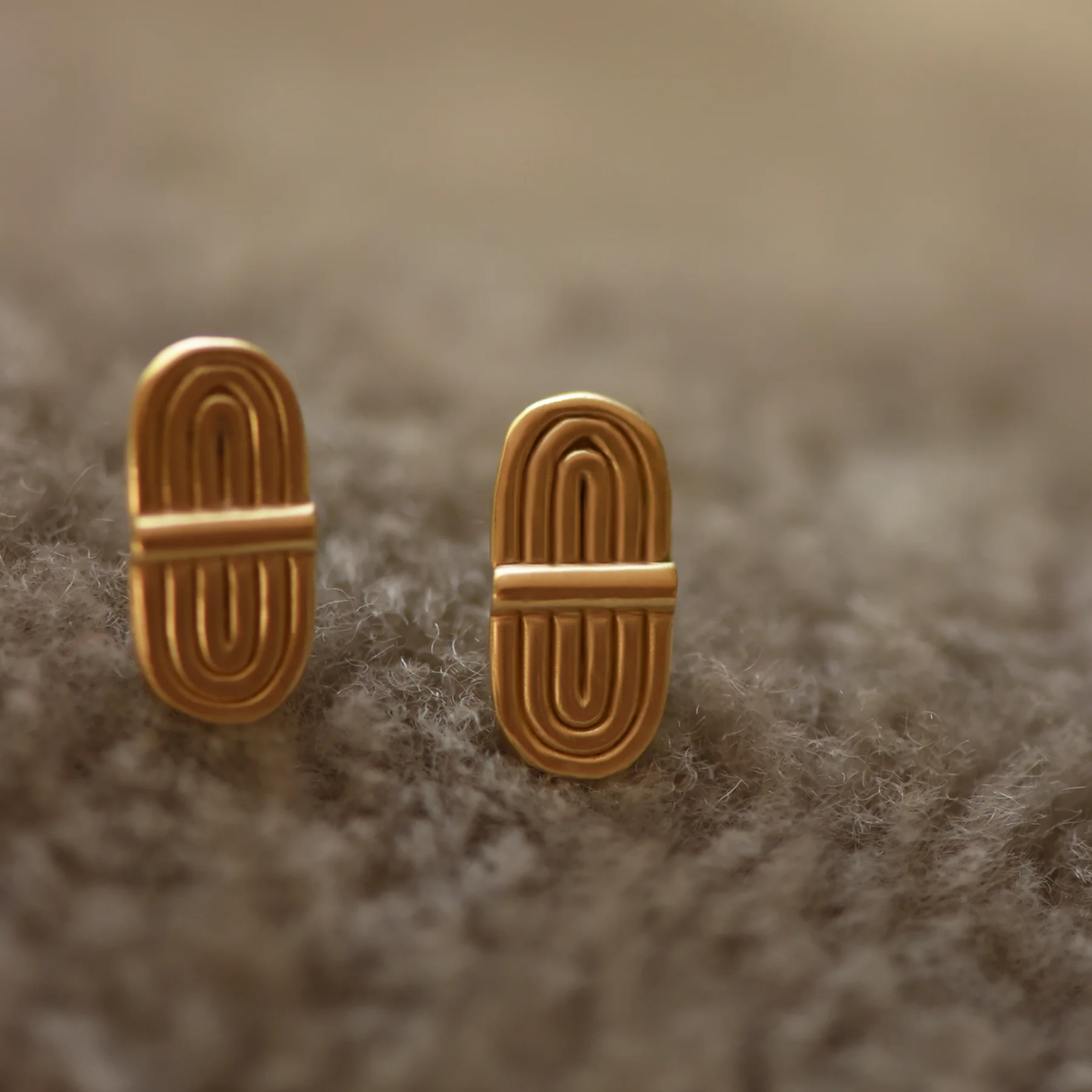 Double-arc brass stud earrings with curved bar fronts, gold-tone backs