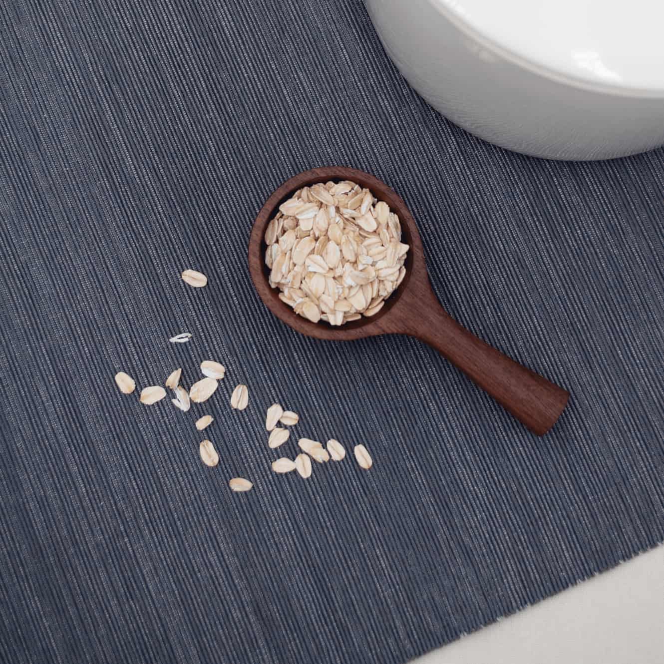 Walnut wood scoop filled with rolled oats in the rounded bowl