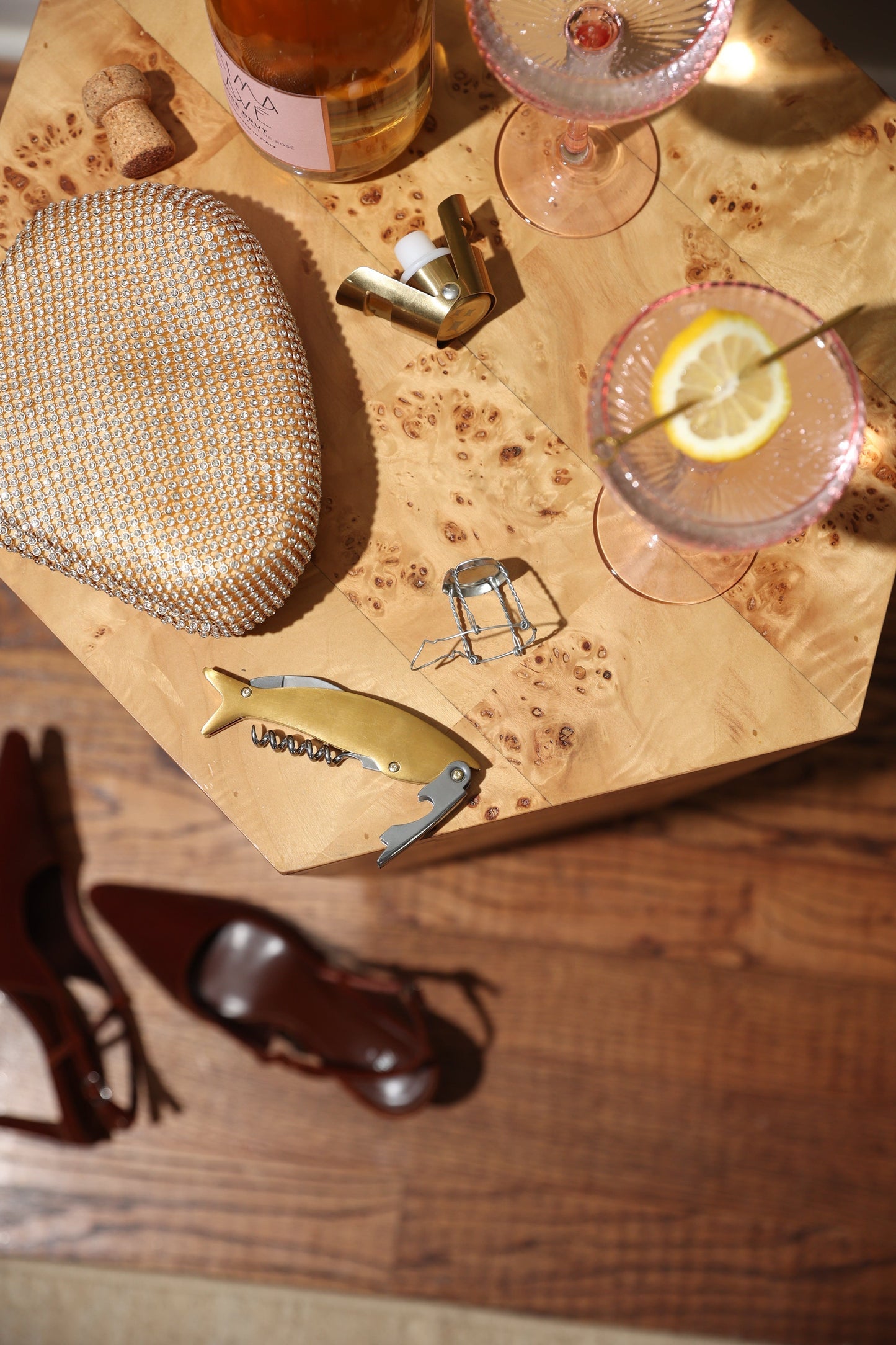 Maple wine bottle opener lying on wooden surface, gold-toned handle with corkscrew