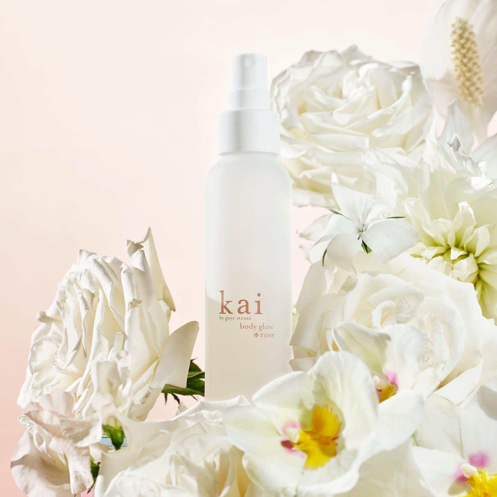 Kai Rose body glow lotion bottle with pump, beside white roses
