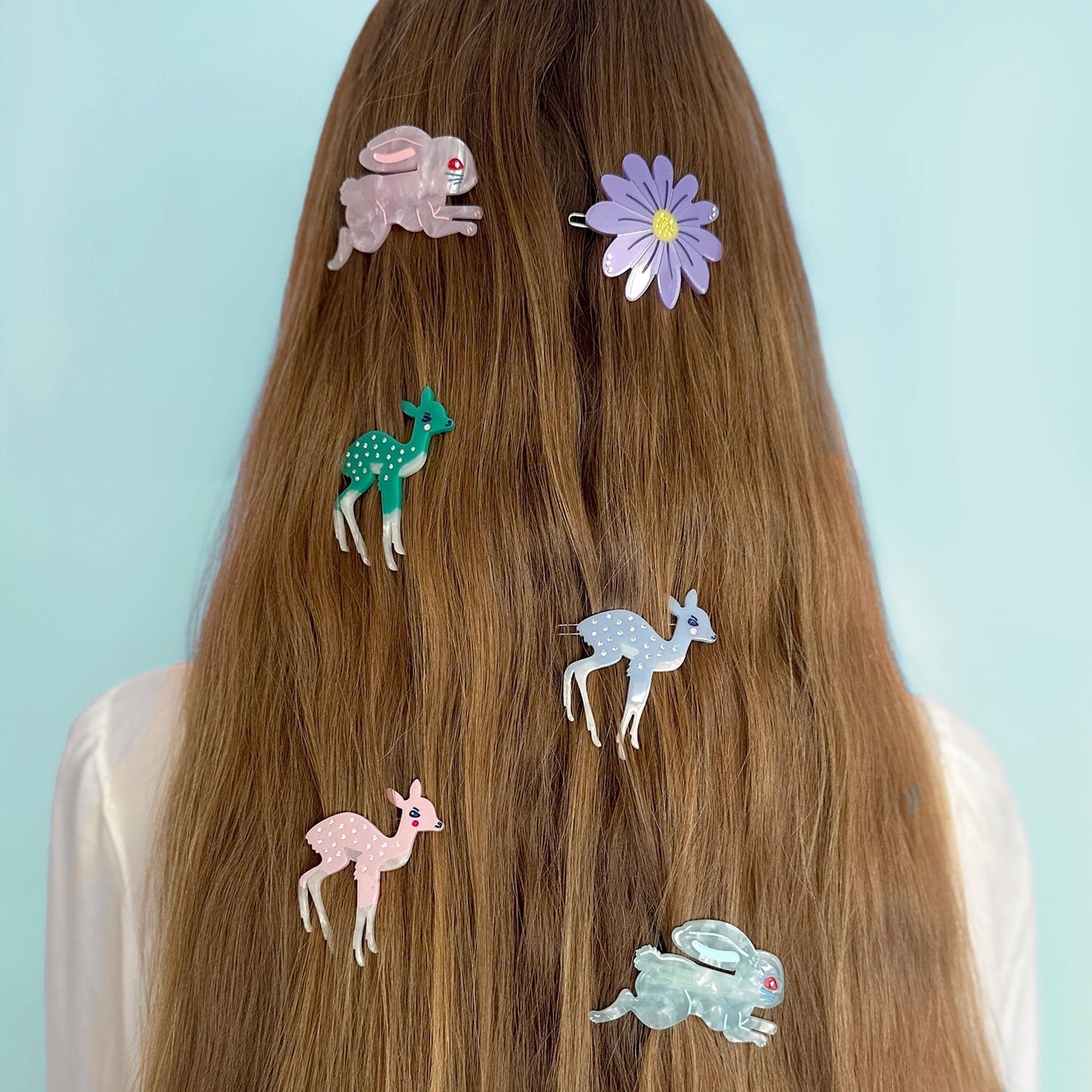 Deer hair clips on brown hair, featuring blue and pink deer shapes