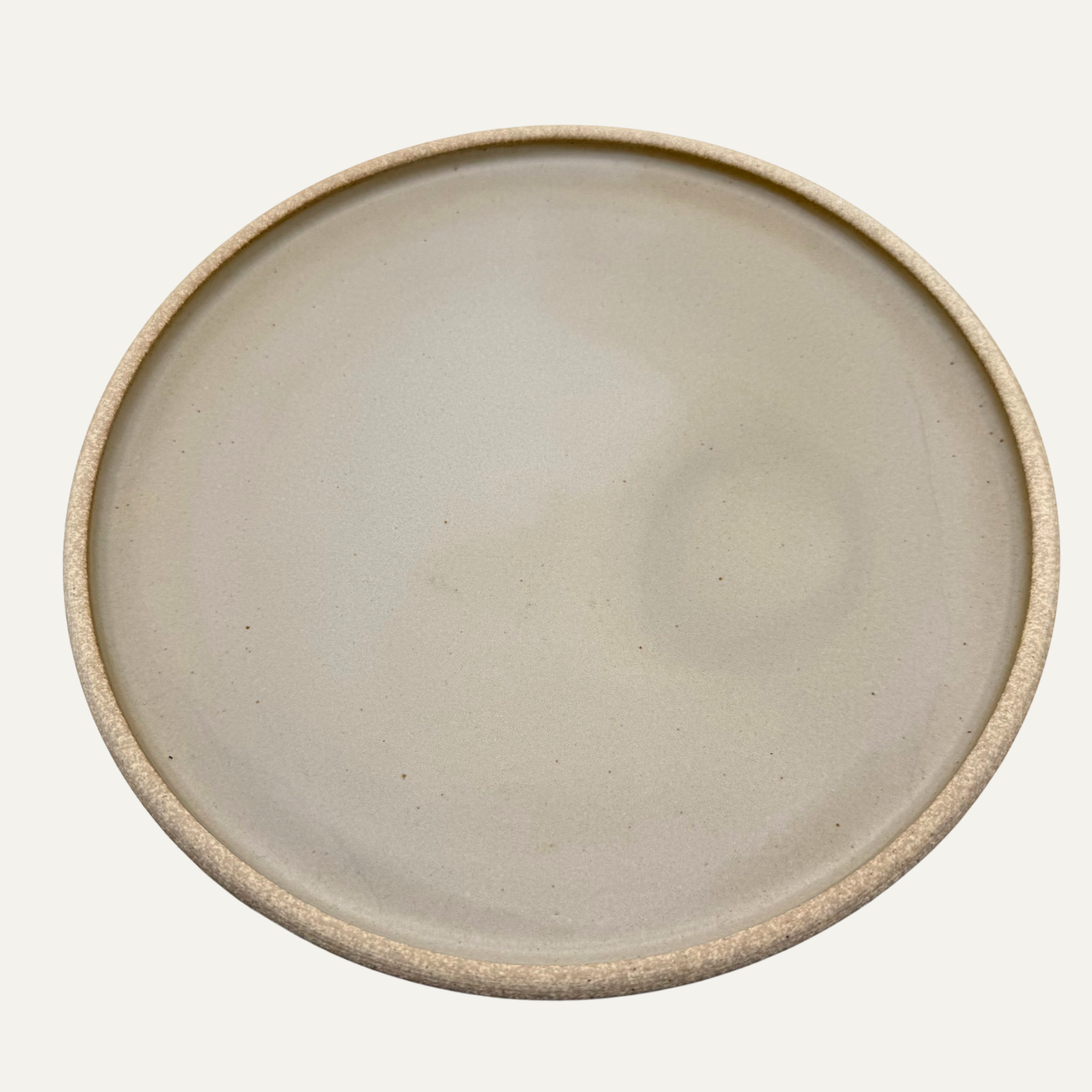 10-inch round matte glazed cream plate with smooth center and speckled edge