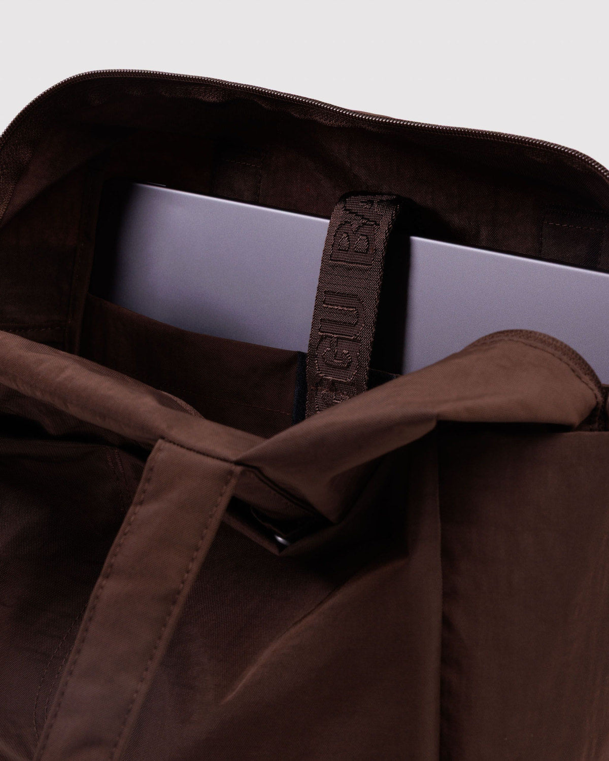 Brown fabric bag interior view with stitched label and zip track