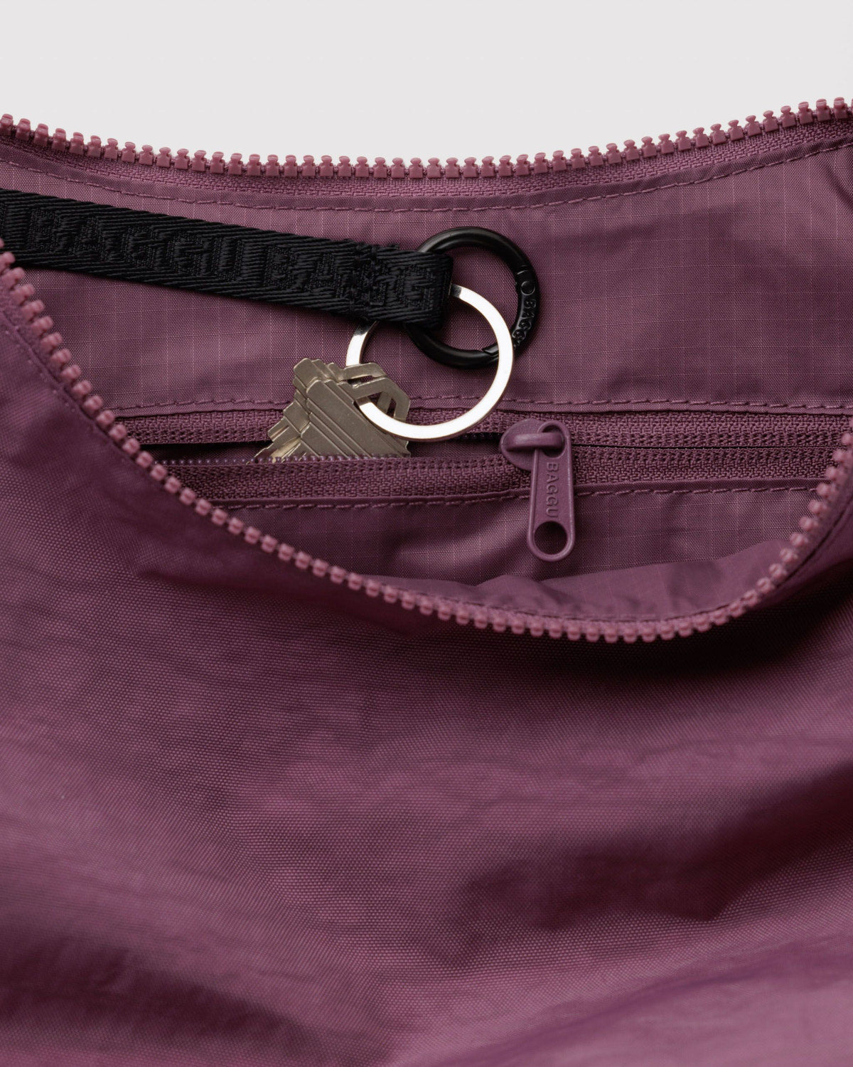 Medium nylon crescent bag interior in plum purple with zipper pull and key ring