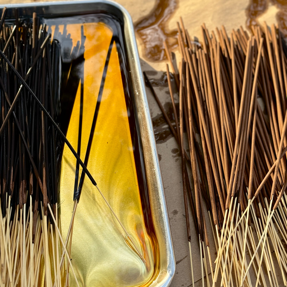 Hand-rolled incense sticks in metal tray with glowing tips