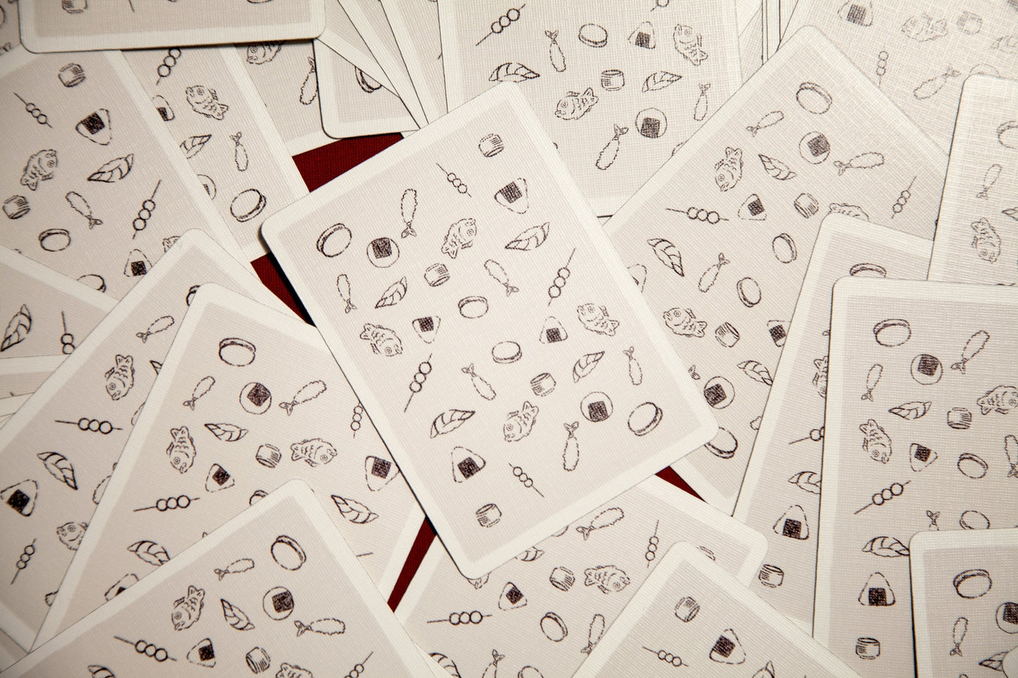 Playing cards laid out with white backs and small gray icons and motifs