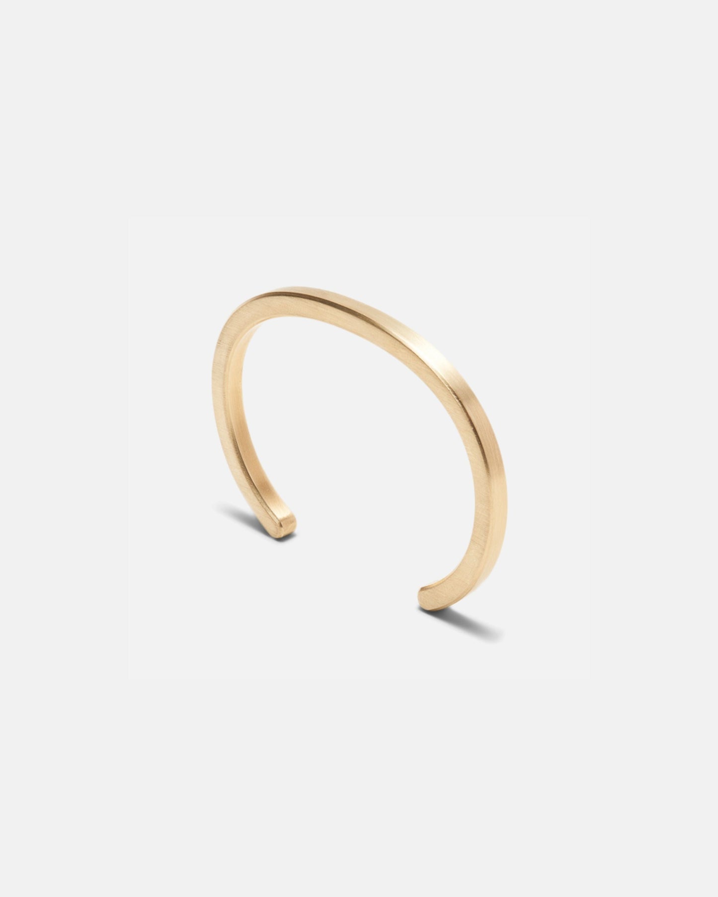 Brass open cuff bracelet shown from side angle, smooth radial profile