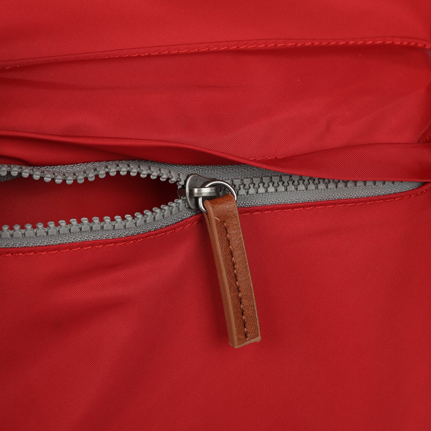 Red nylon crossbody top zipper with gray zipper teeth and brown pull tab