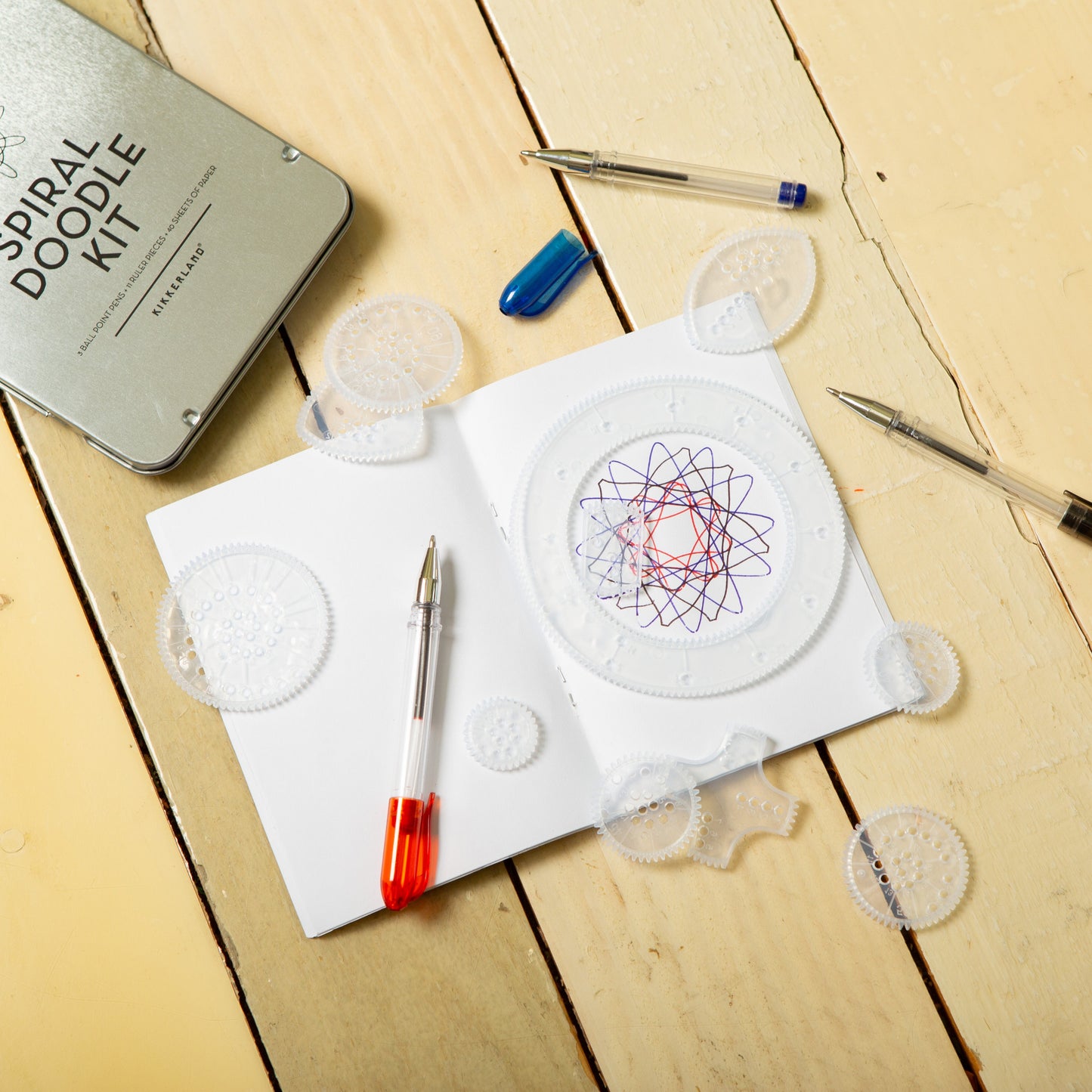 Doodle supplies on papers: white perforated shapes, blue marker, pens and cards.