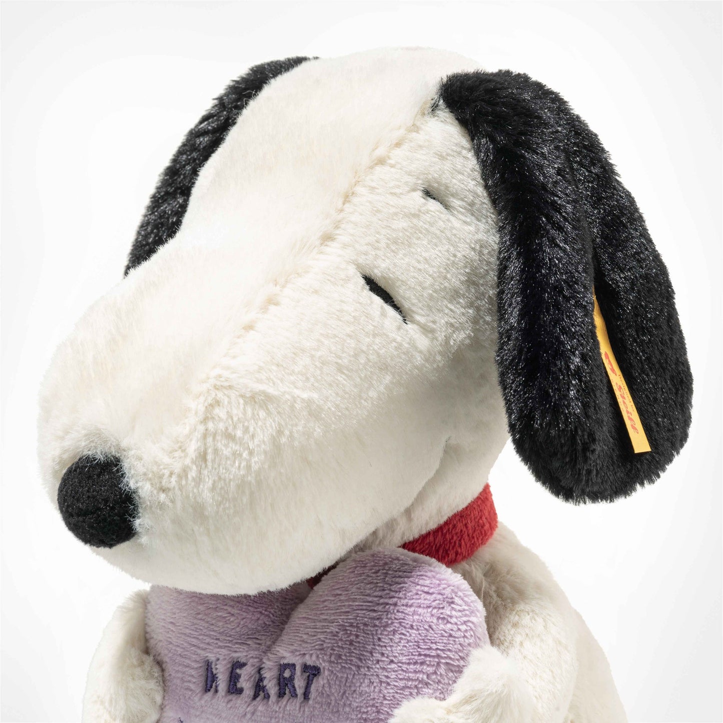 Plush dog toy close-up with black ear, red collar, and purple Heartbreakers Club heart