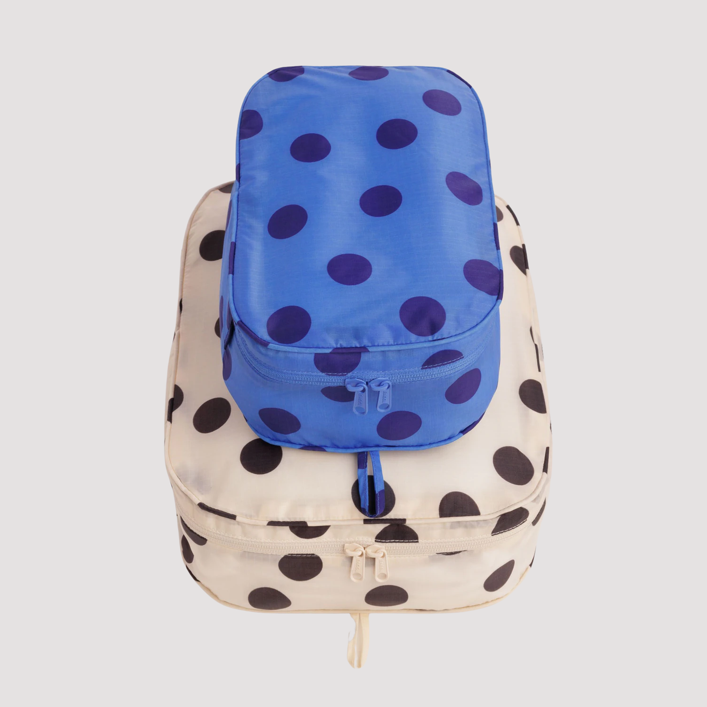 Packing cube set with blue polka-dot cube and beige black-dot cube, zip closure.