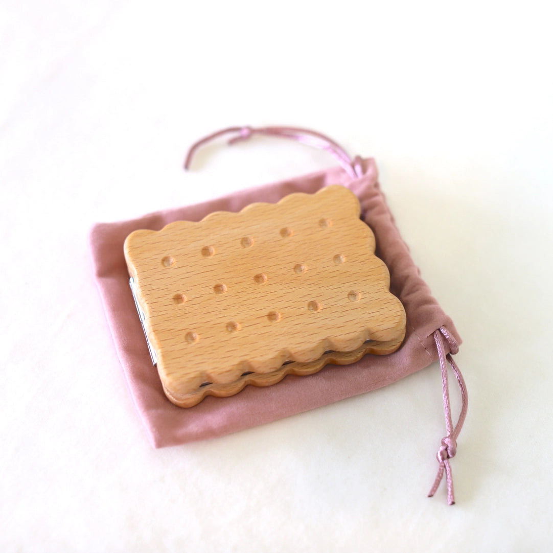 Beech wood biscuit compact mirror in a pink drawstring pouch, tied with ribbon.
