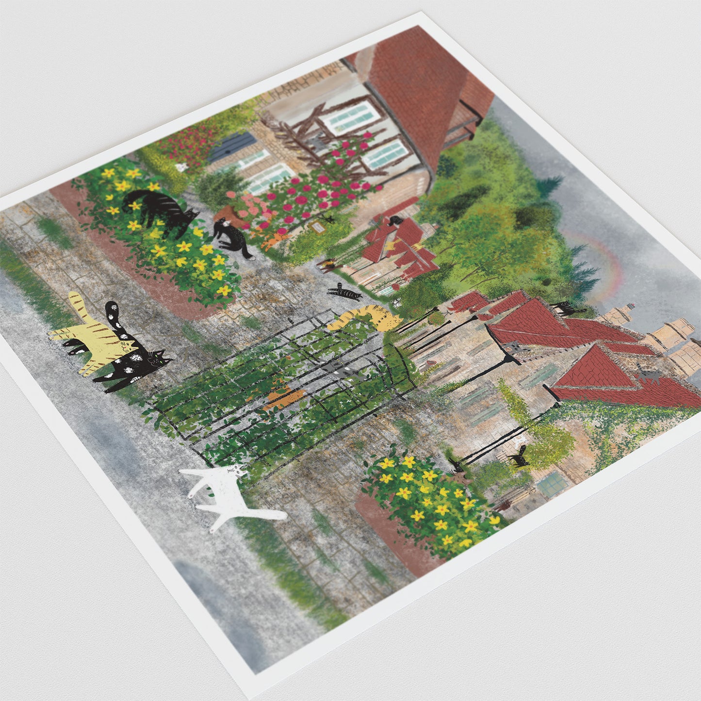 Unframed art print, angled view, cats among flowers and red-roof houses