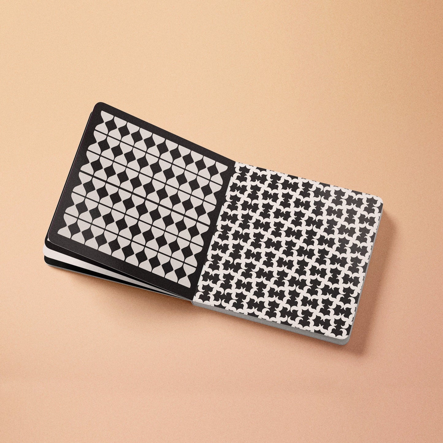 High-contrast baby board book open, black-and-white grid and repeating puzzle pattern