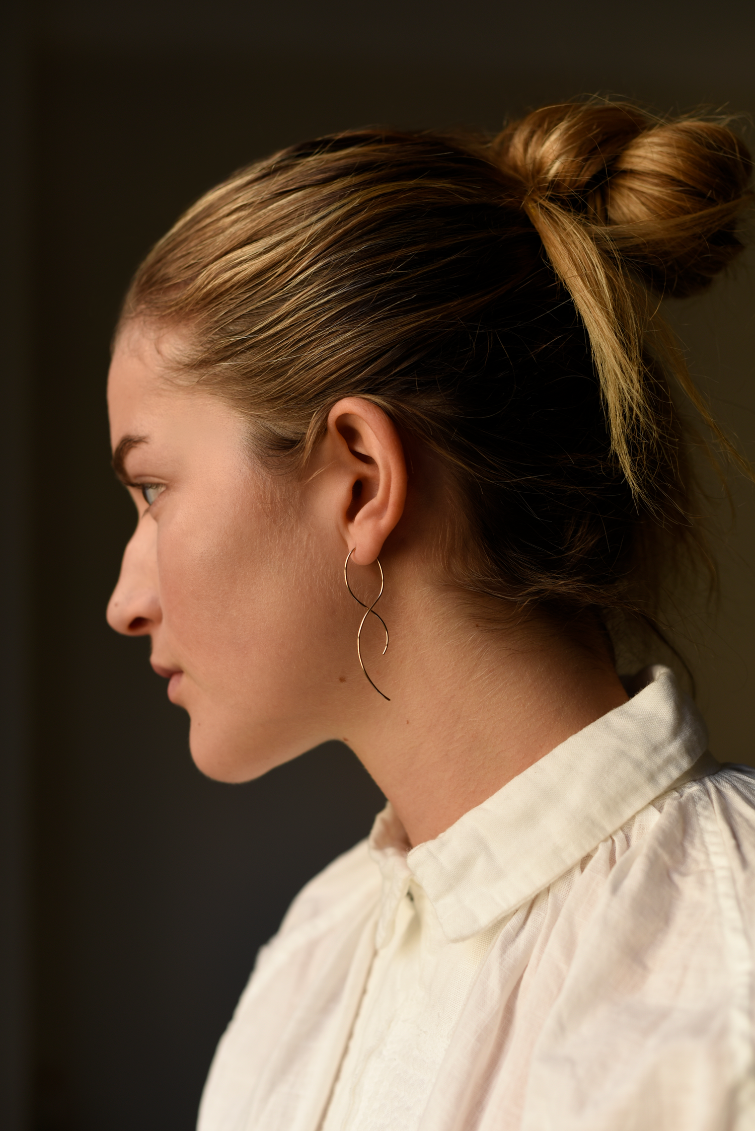 Gold twist threader earrings worn on ear, thin open hoop wire