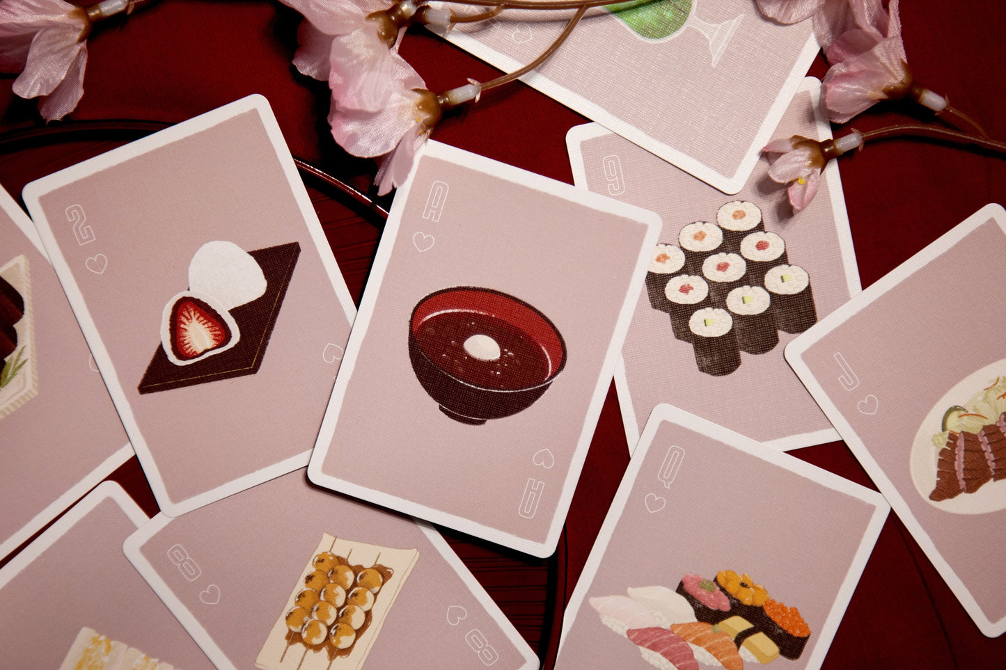 Playing cards fanned out with red and brown food-themed face cards in rounded frames