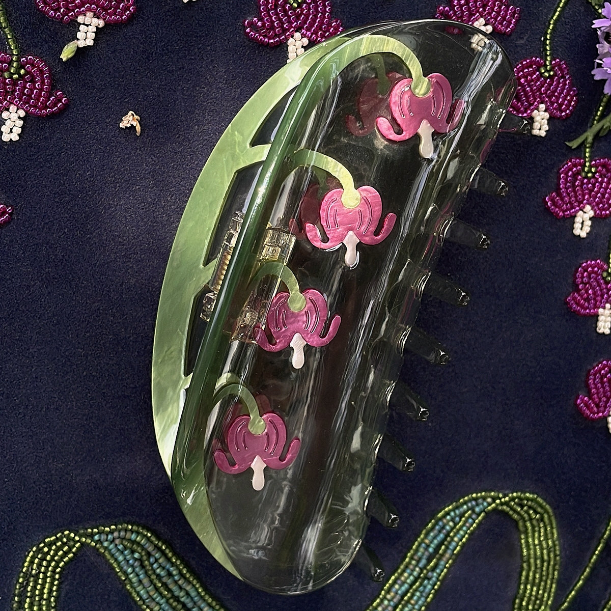 Long hair claw clip close-up, transparent with green edge and pink floral decorations
