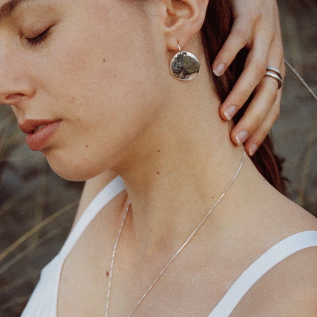 Silver round hammered hook earring worn by model