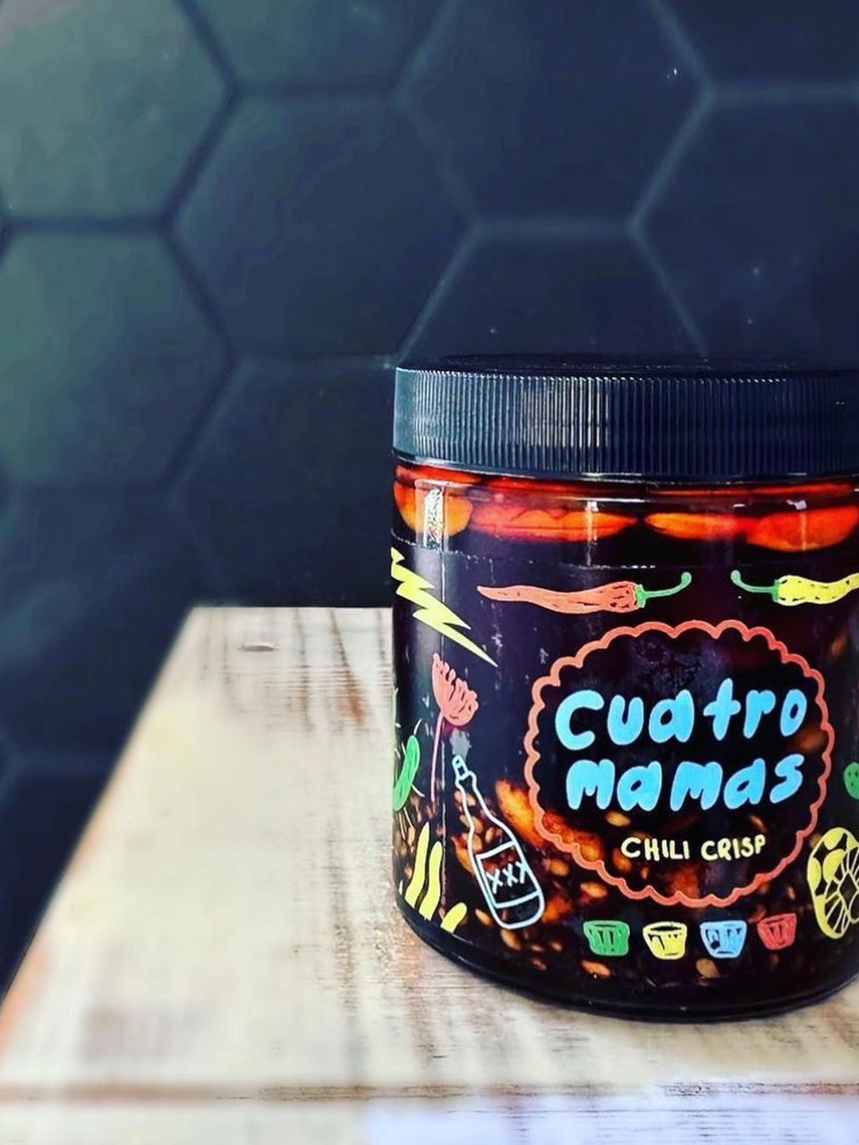 Chili crisp jar with dark label and ribbed metal lid, mild chili crisp close-up