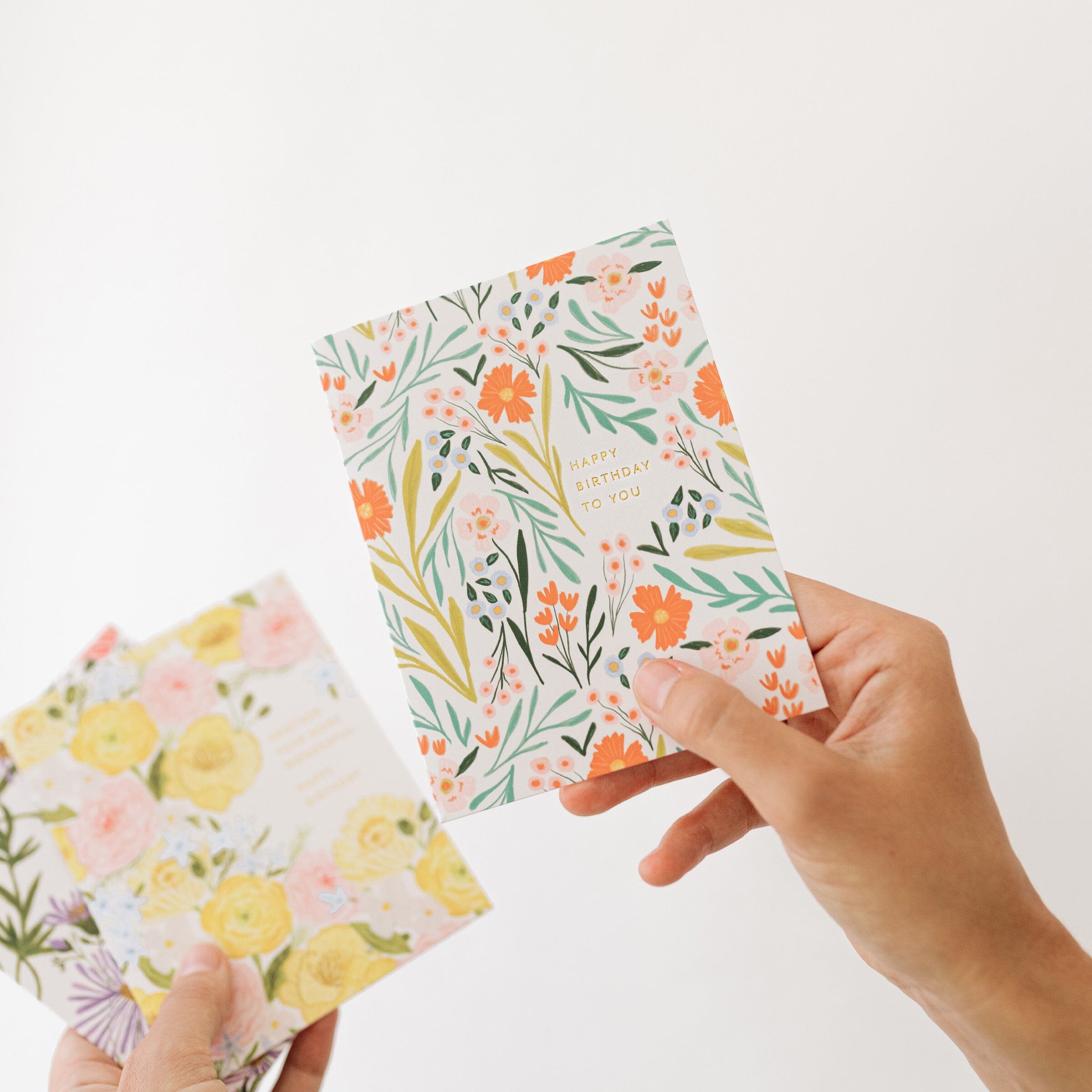Botanical birthday card held in hand, white floral design with birthday greeting text