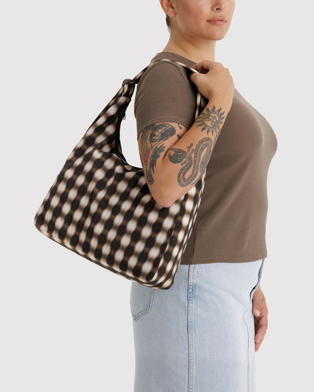 Gingham nylon shoulder bag held on shoulder, showing tan-and-brown check pattern
