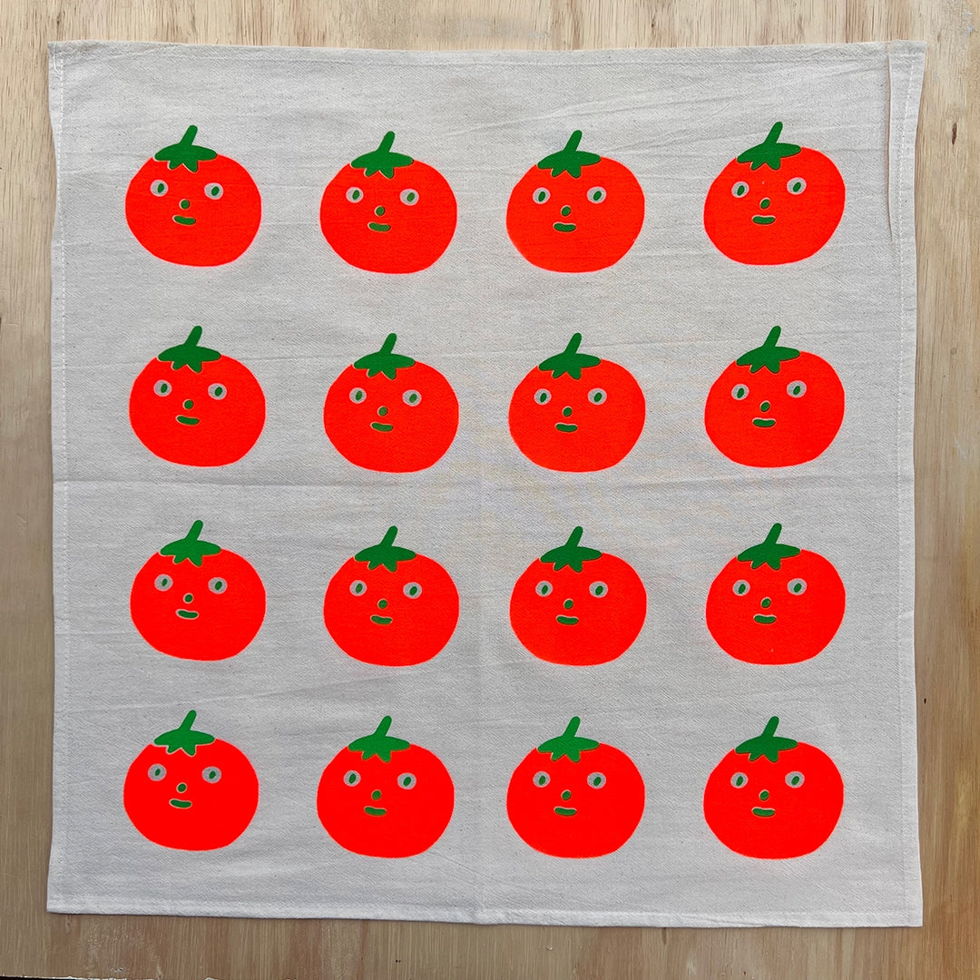 Gray cotton tea towel with repeating red tomato faces and green leaves pattern