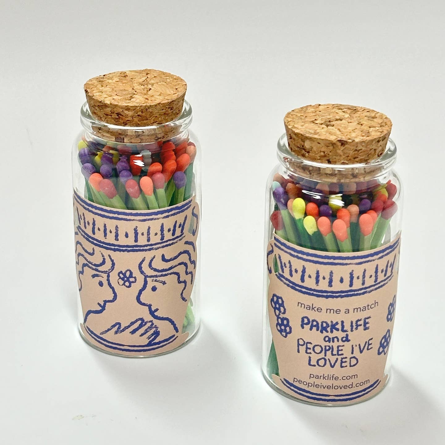 Decorative glass match jars with cork lids, colorful matchsticks and illustrated label