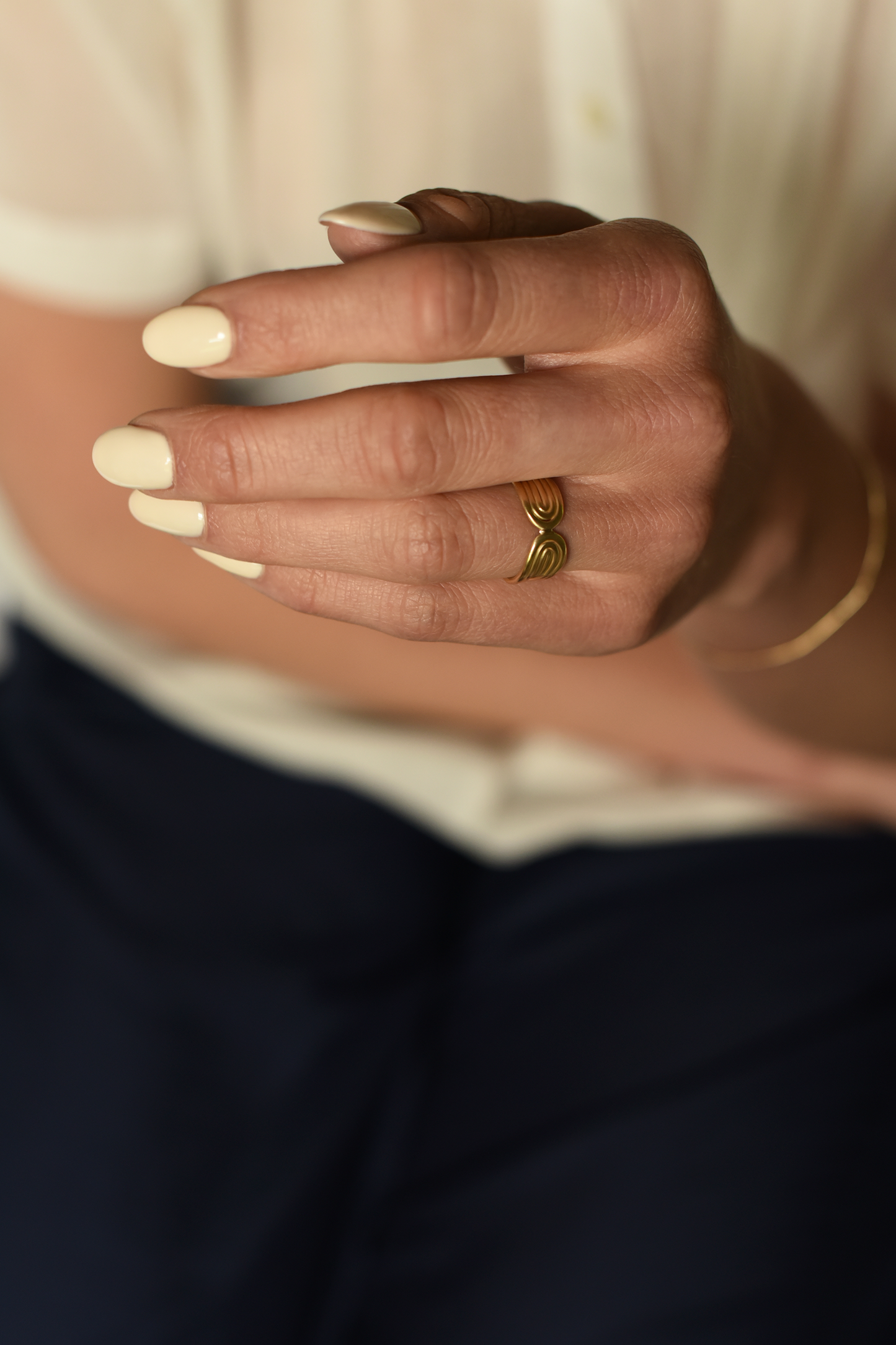 Gold sculpted double-arc ring worn on finger, rounded band with arc grooves