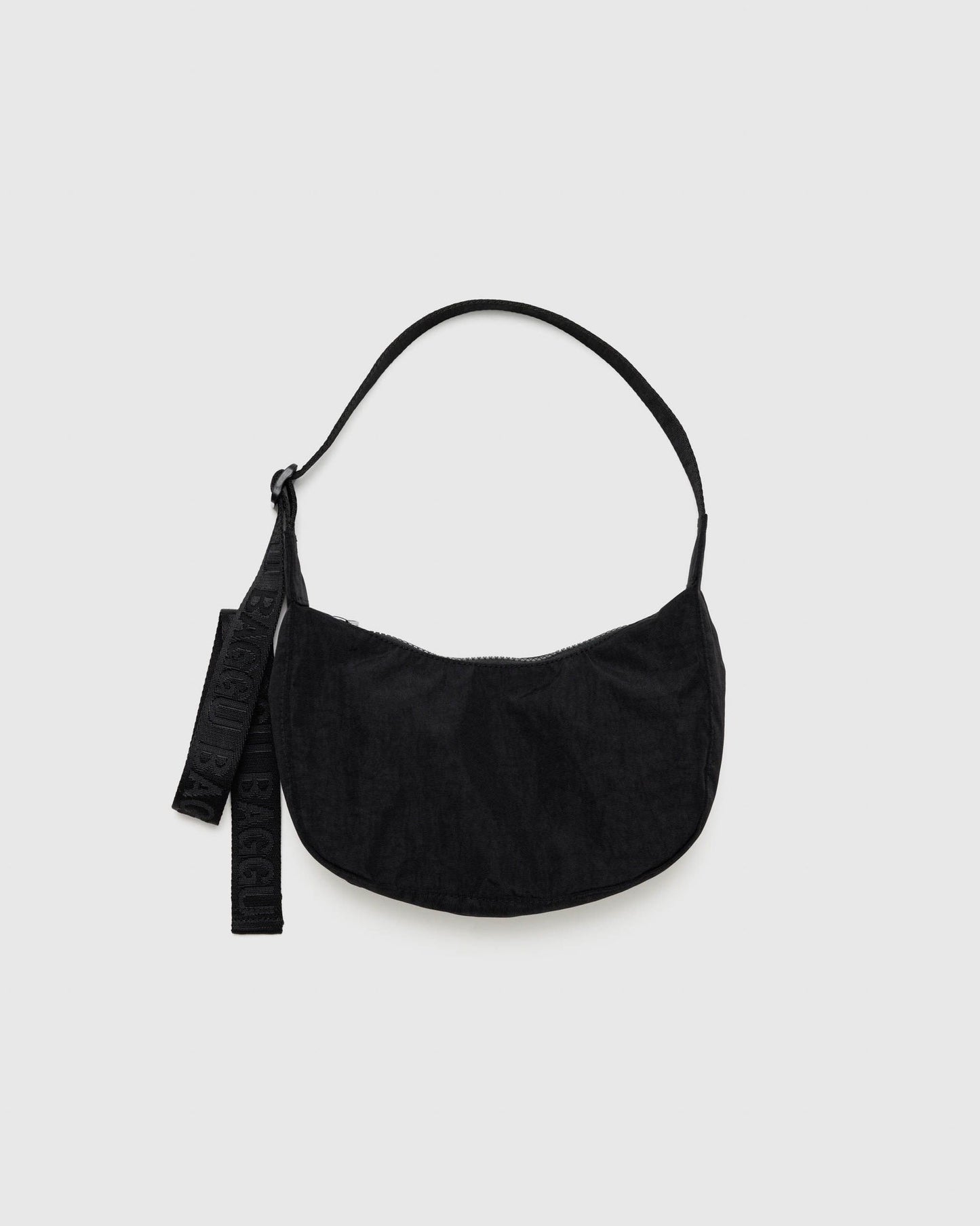 Small crescent nylon crossbody bag in black with curved shoulder strap and hanging tag